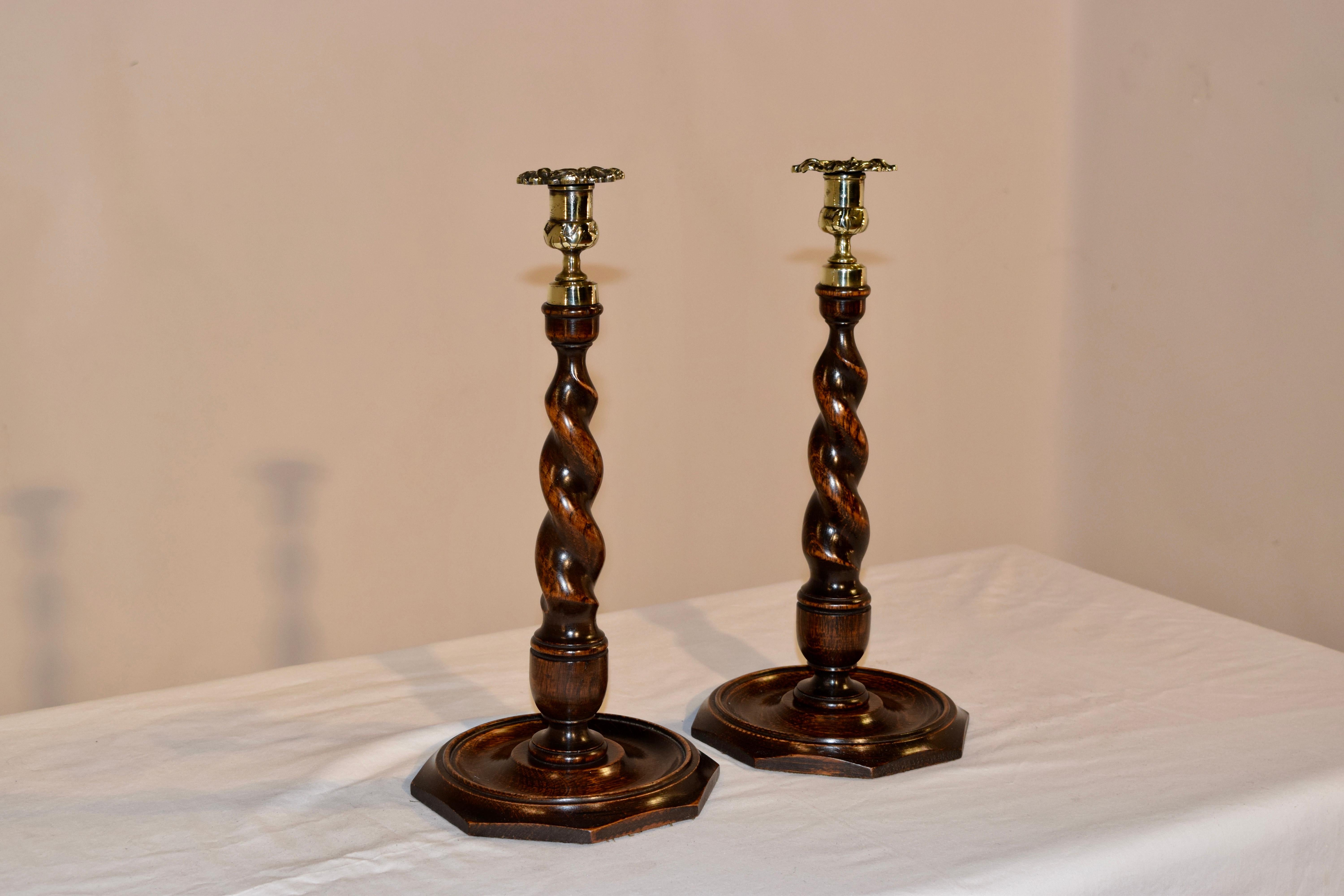 Pair of 19th century tall candlesticks from England made from oak. The candle cups are hand cast from brass and follow down to hand-turned graduated barley twist candlesticks with vase shaped turnings at the base, where they sit atop hand-turned