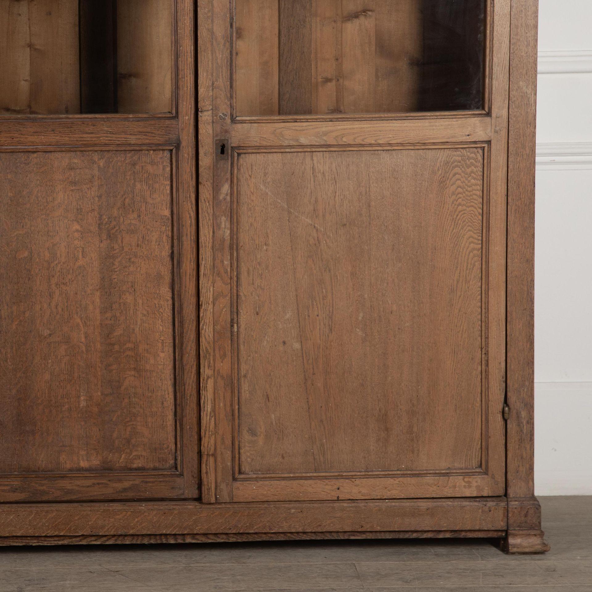 Pair of 19th Century tall oak bookcases, the interior has adjustable shelves enclosed by glazed and panelled doors.

The moulded cornice above twin-part glazed doors encloses an interior with adjustable shelves, having panelled sides and supported