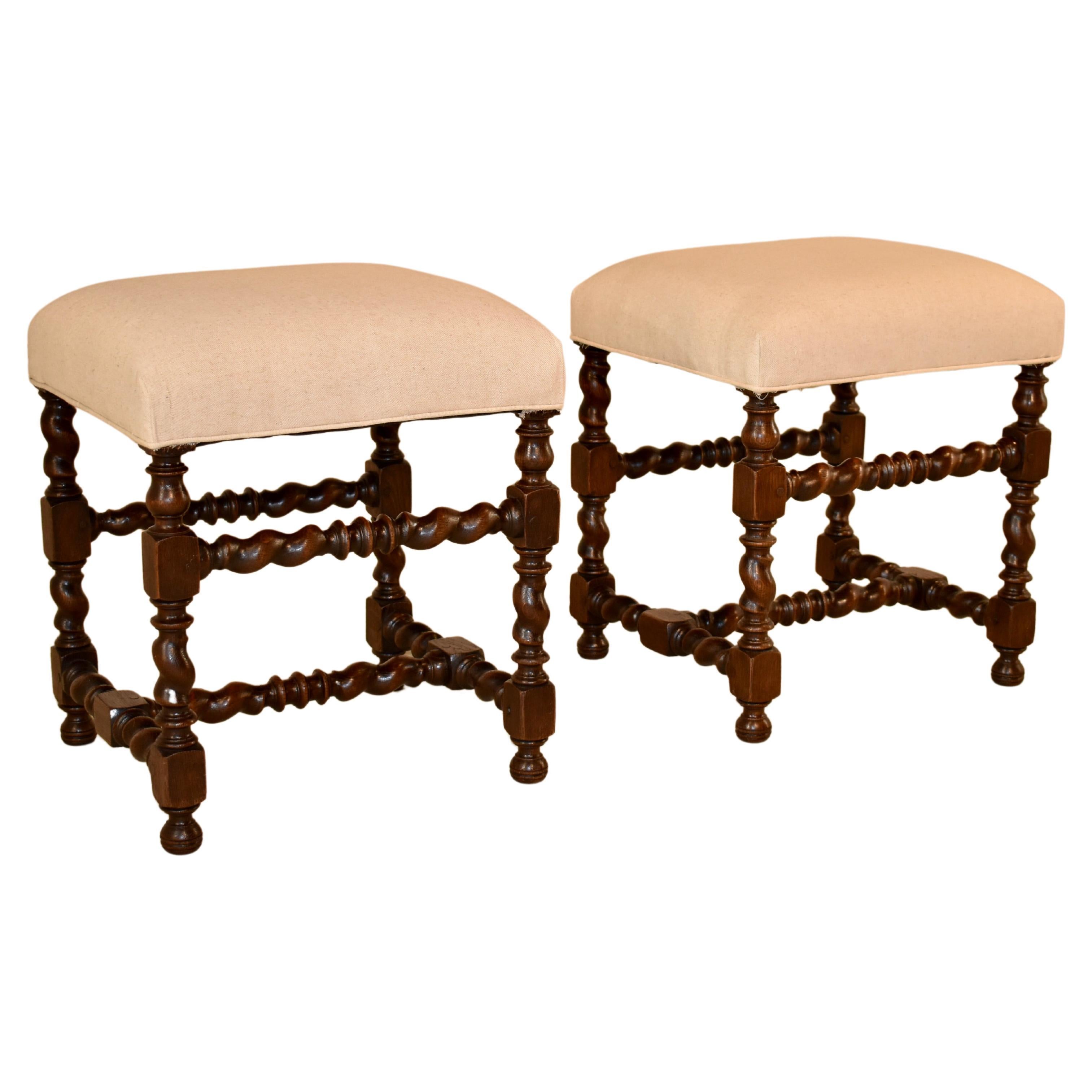 Pair of 19th century oak stools from France with newly upholstered tops in linen finished with a single welt. The frames have hand-turned barley twist legs, joined by matching stretchers and raised on small bun feet.