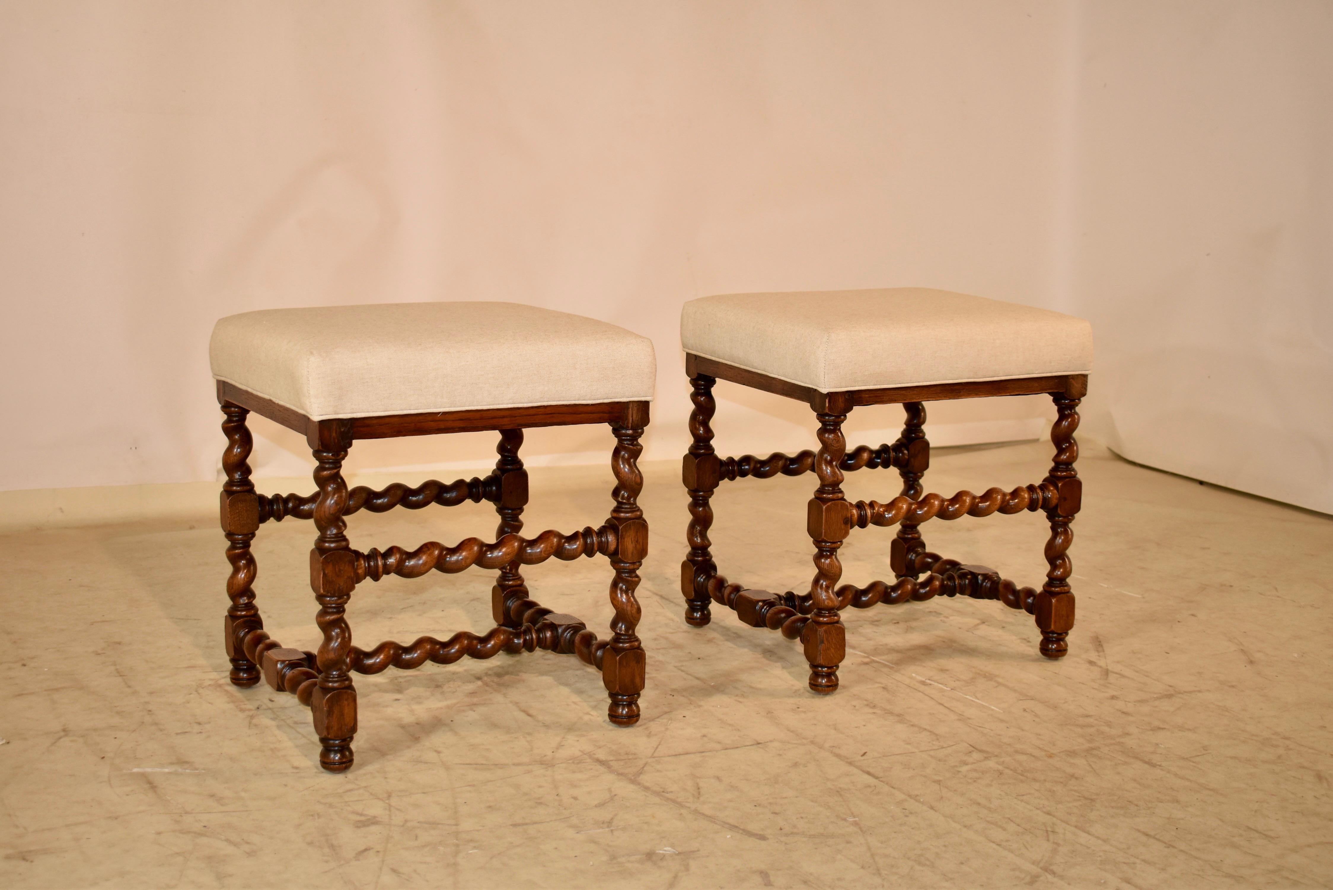 Pair of 19th century oak stools from France with newly upholstered tops in linen finished with a single welt. The frames have hand-turned barley twist legs, joined by matching stretchers and raised on small bun feet.