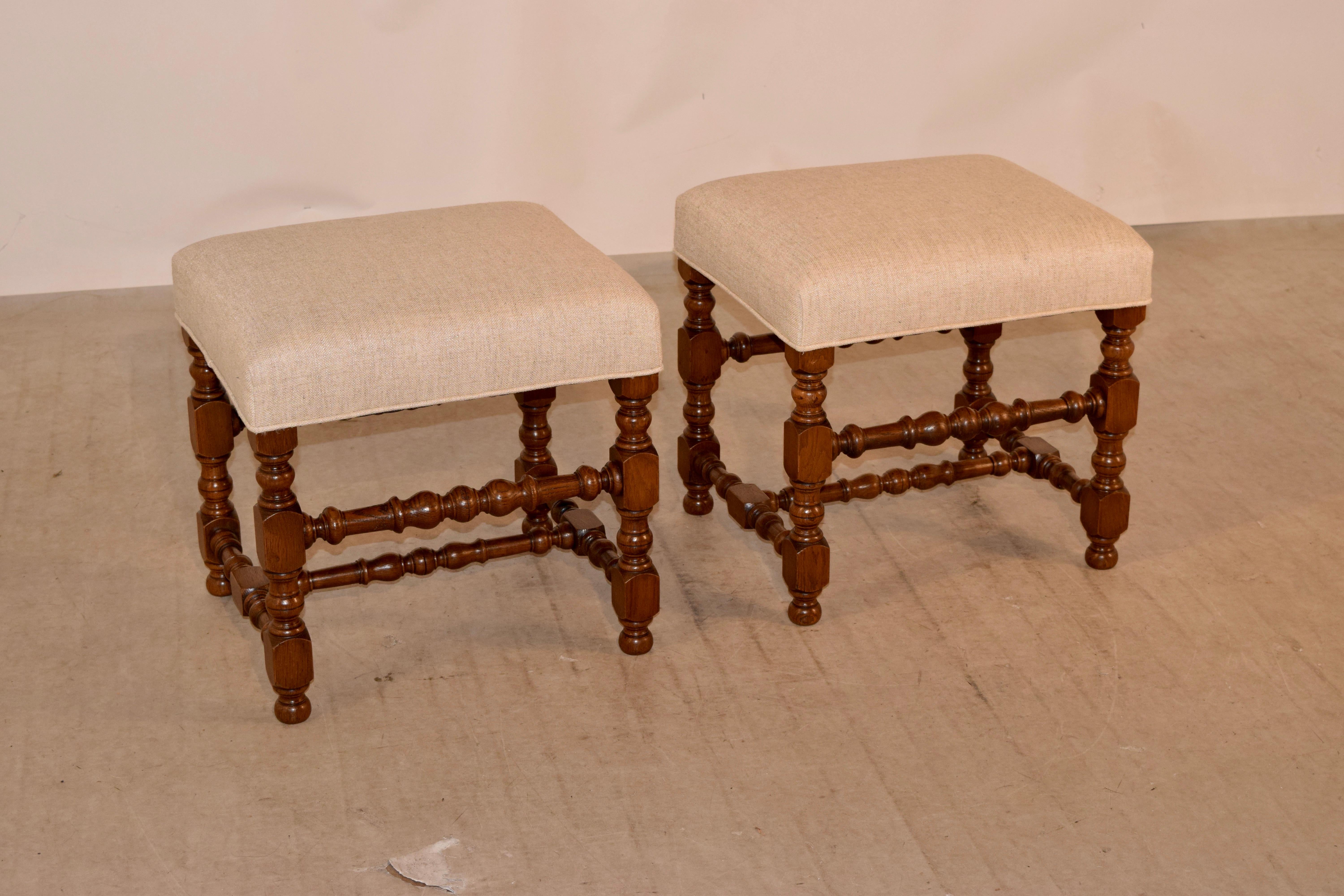 Pair of 19th century oak stools from France with newly upholstered tops in linen finished with a single welt. The frames have hand-turned oak legs, joined by hand-turned stretchers and raised on small bun feet.