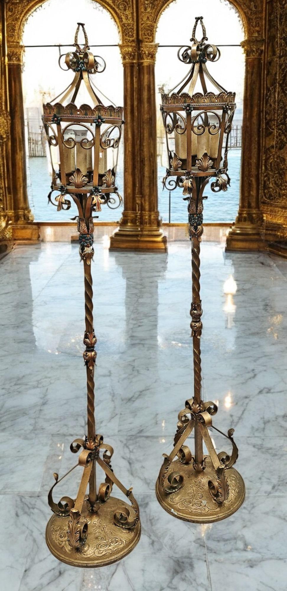 A beautiful pair of 19th Century Italian Venetian tole lanterns. Hand-forged of wrought iron, the lanterns are embellished with acanthus leaves and flower blooms, supported by a twisted rope center pole, anchored to a round heavy base. The inside of