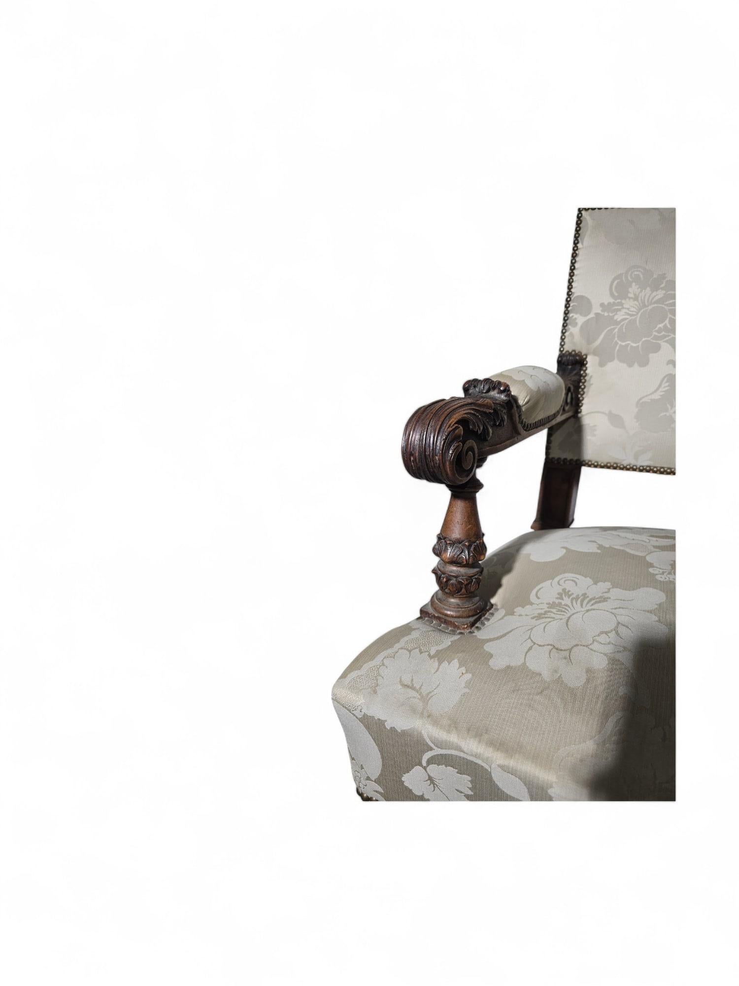 Questa elegante coppia di poltrone in noce del XIX secolo è un bellissimo esempio di design e artigianato senza tempo. Ispirate agli stili dell'inizio del XVIII secolo, queste sedie sono caratterizzate da braccioli e gambe finemente intagliati, che