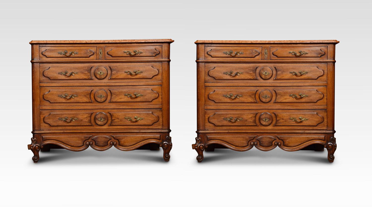 A pair of 19th century French walnut commodes, the large rectangular Rosa Verona marble tops with rounded corners above an arrangement of three long and two short molded paneled drawers with cast scrolling acanthus handles and original locks and