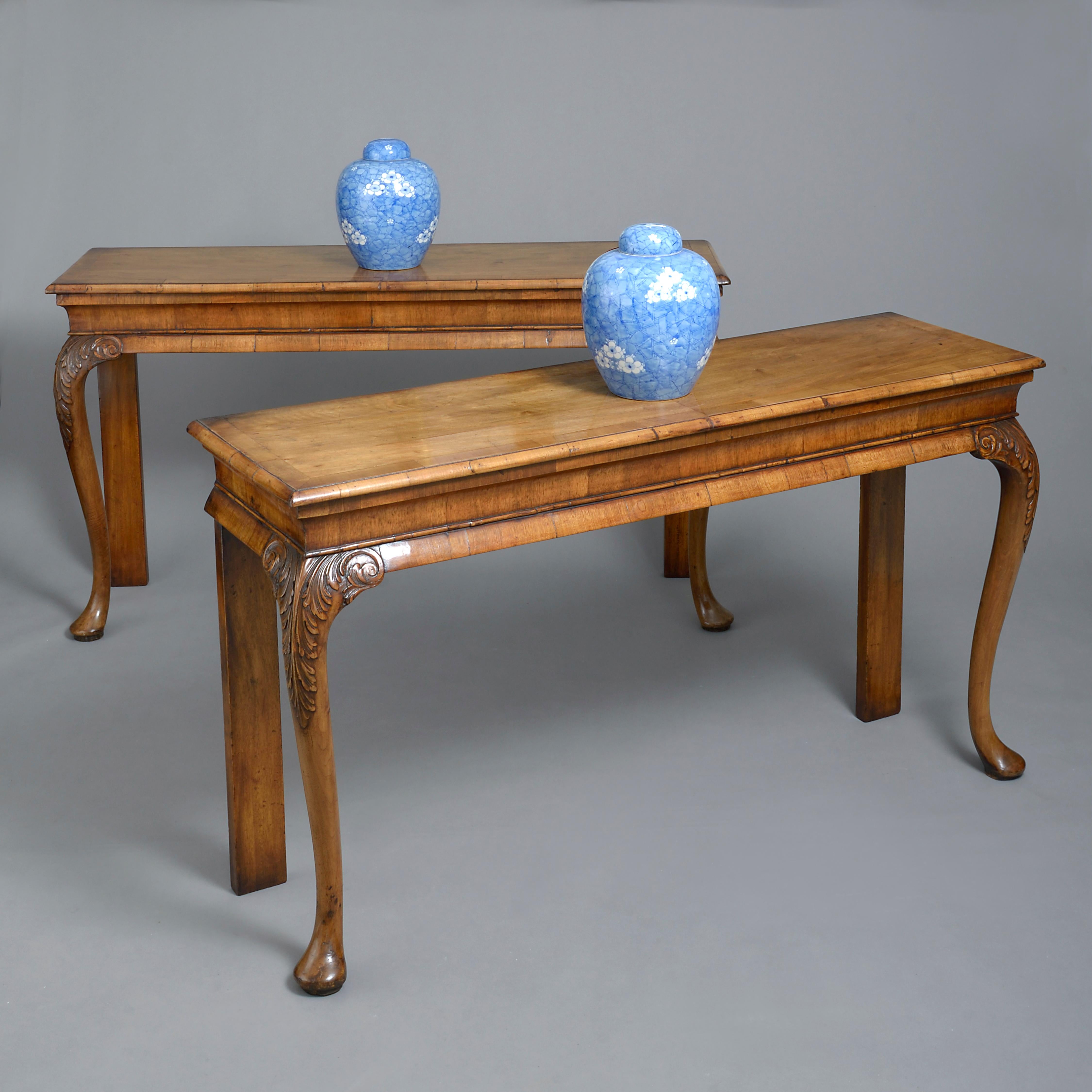 A fine pair of late 19th century pier tables in the George I manner, each crossbanded veneered top above a frieze and set upon finely carved cabriole legs with acanthus carving and pad feet.

 