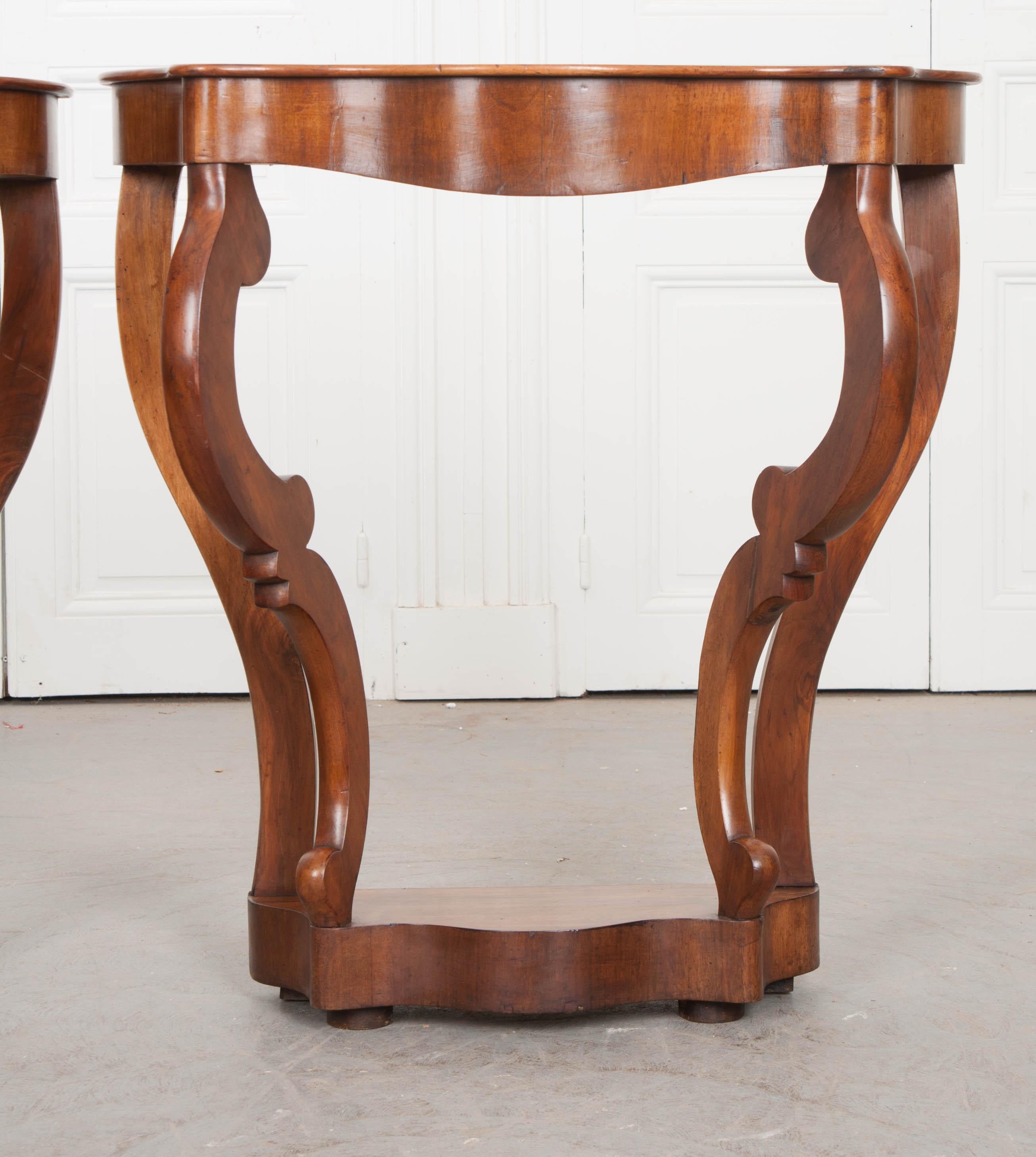 A smart pair of restauration style walnut consoles from 19th century France. They are demilune in form and have a shapely top. Similarly, the legs have a curved and styled design that is interesting and absolutely stunning. The walnut veneer has