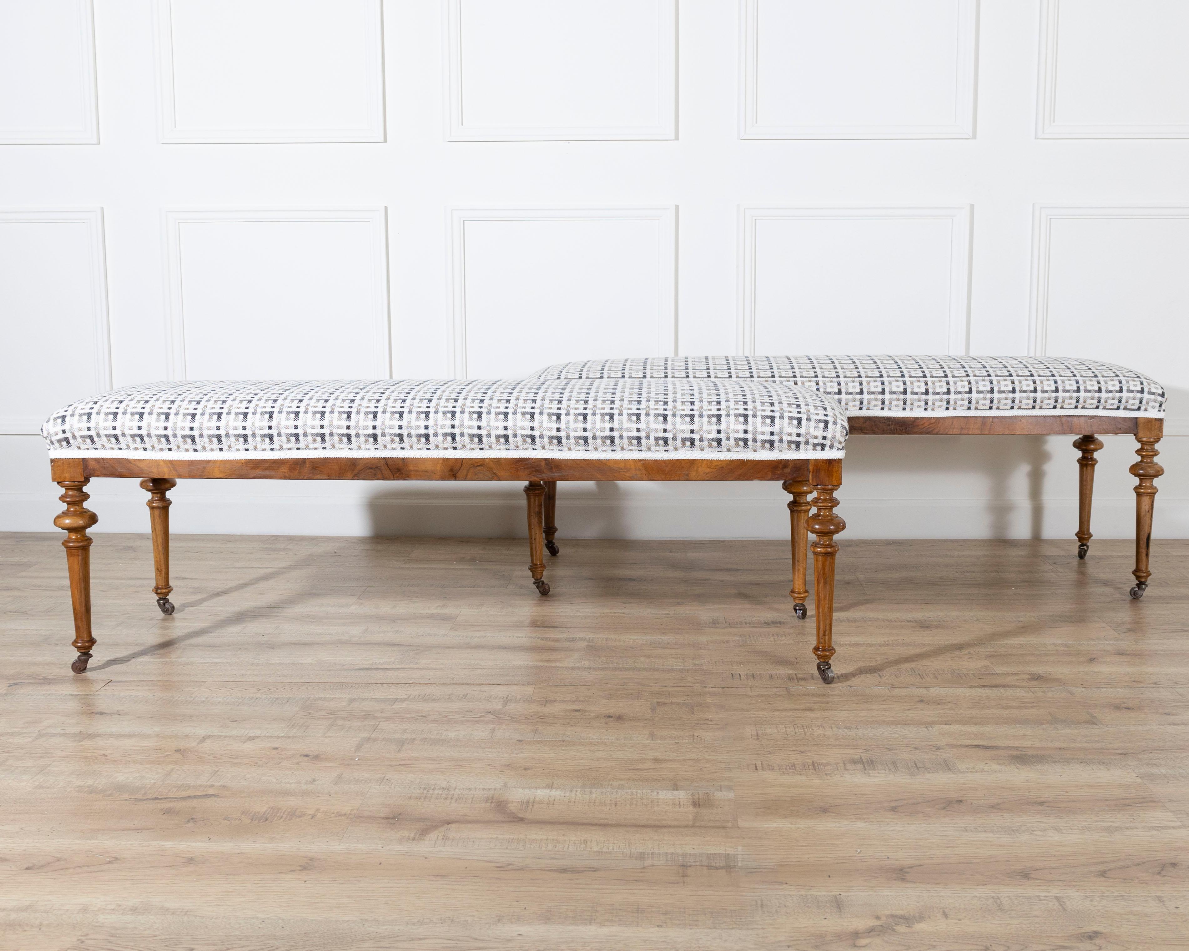 A beautiful pair of 19th-century benches crafted in warm blond walnut, featuring finely turned and twisted legs that terminate in their original brass casters. The benches display exceptional craftsmanship and elegant proportions, blending lightness