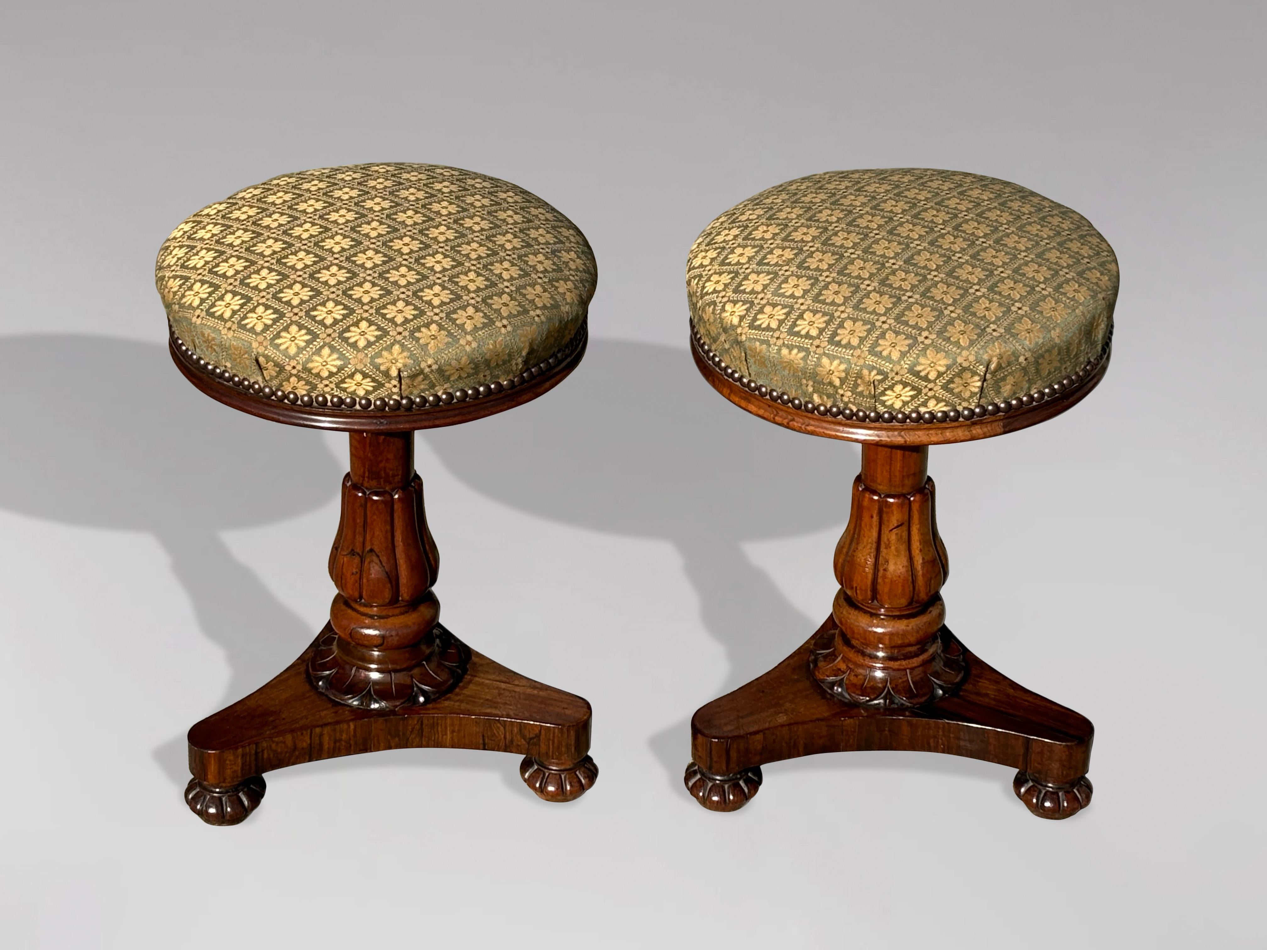 A pair of fine quality 19th-century William IV period rosewood piano or duet stools. Each features an adjustable-height round seat, recently reupholstered, positioned above a finely shaped tripod base. The stools are raised on a turned column with a