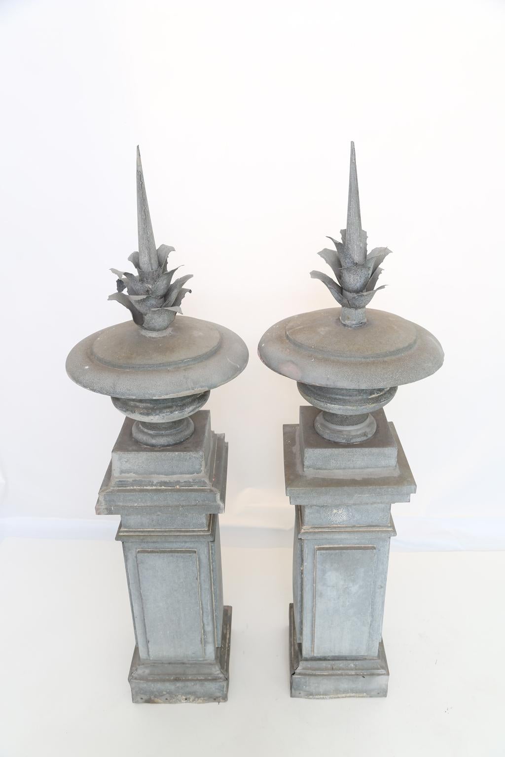 Pair of 19th century architectural finials, of zinc metal building finials, each an exaggerated round urn with stylized foliate spire, on tall, square plinths.

Stock ID: D2603.