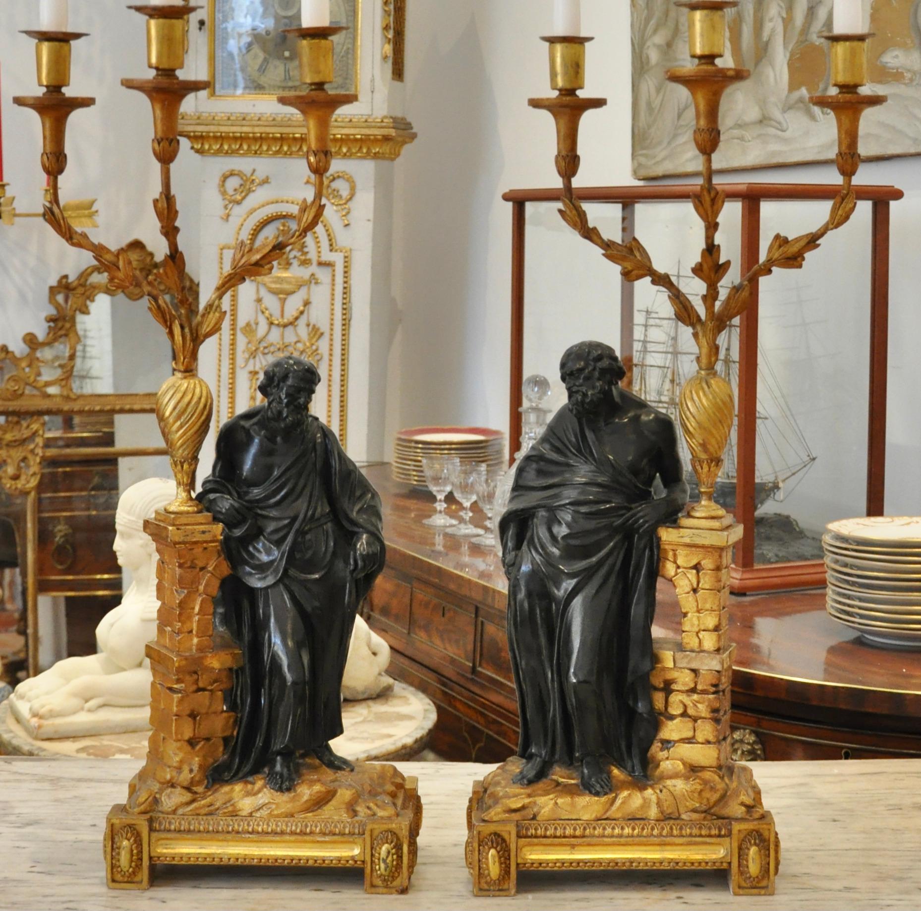 Rare pair of Irish Late Georgian giltwood candelabra of Socrates and Plato. Carved and gilt wooden bases and classical Romantic arches with laurel leafed iron arms issuing from neoclassical urn. Figure of Socrates and Plato in bronzed plaster