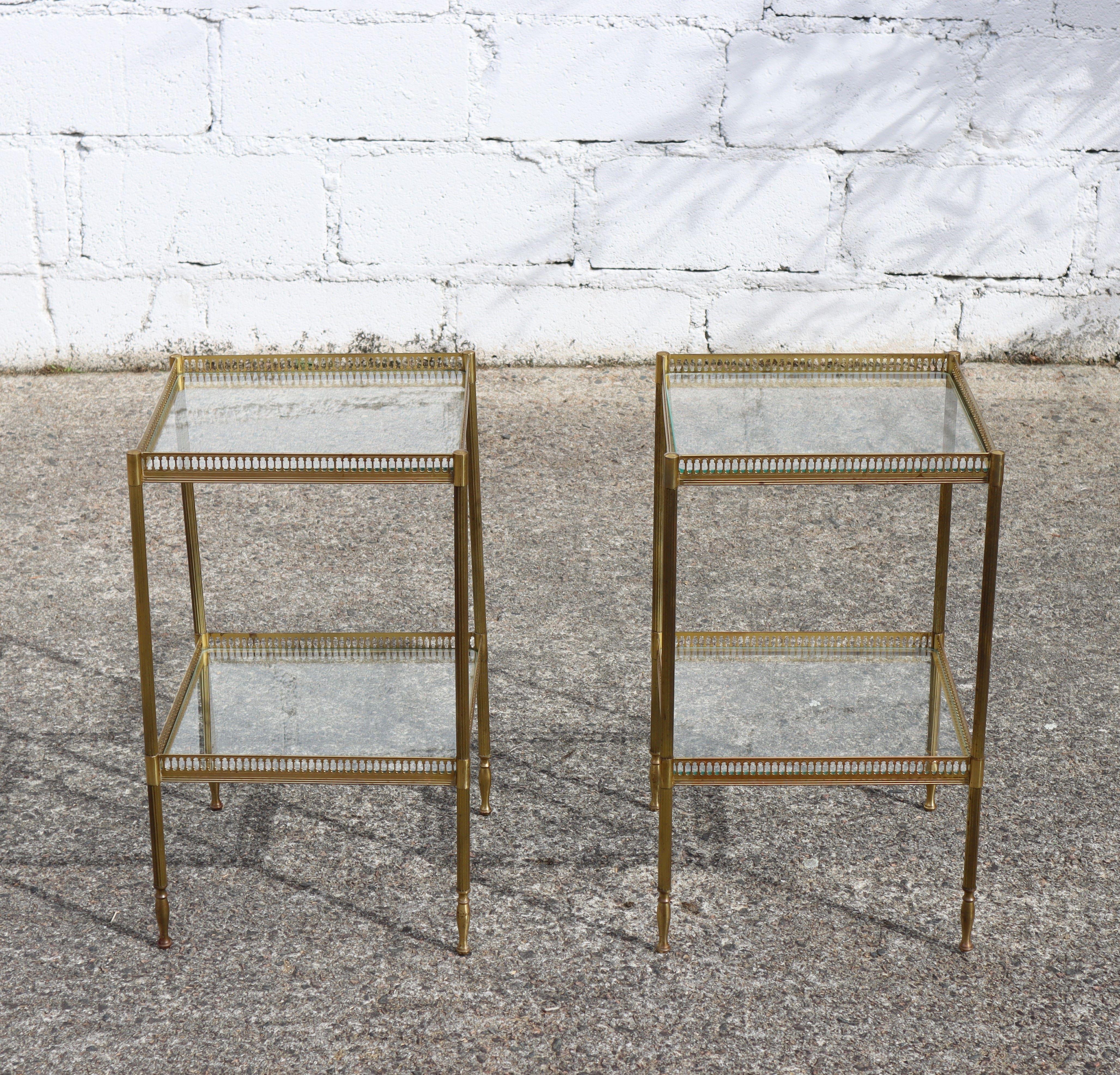 French Pair of 2 Modern Neoclassical double Level Brass and Glass Consoles  Side Tables -Style Maison Jansen from the 50s.
Elegant Design - with two Levels of clear Glass surrounded by a narrow ornamented Brass Railing.
2 beautiful unique Side
