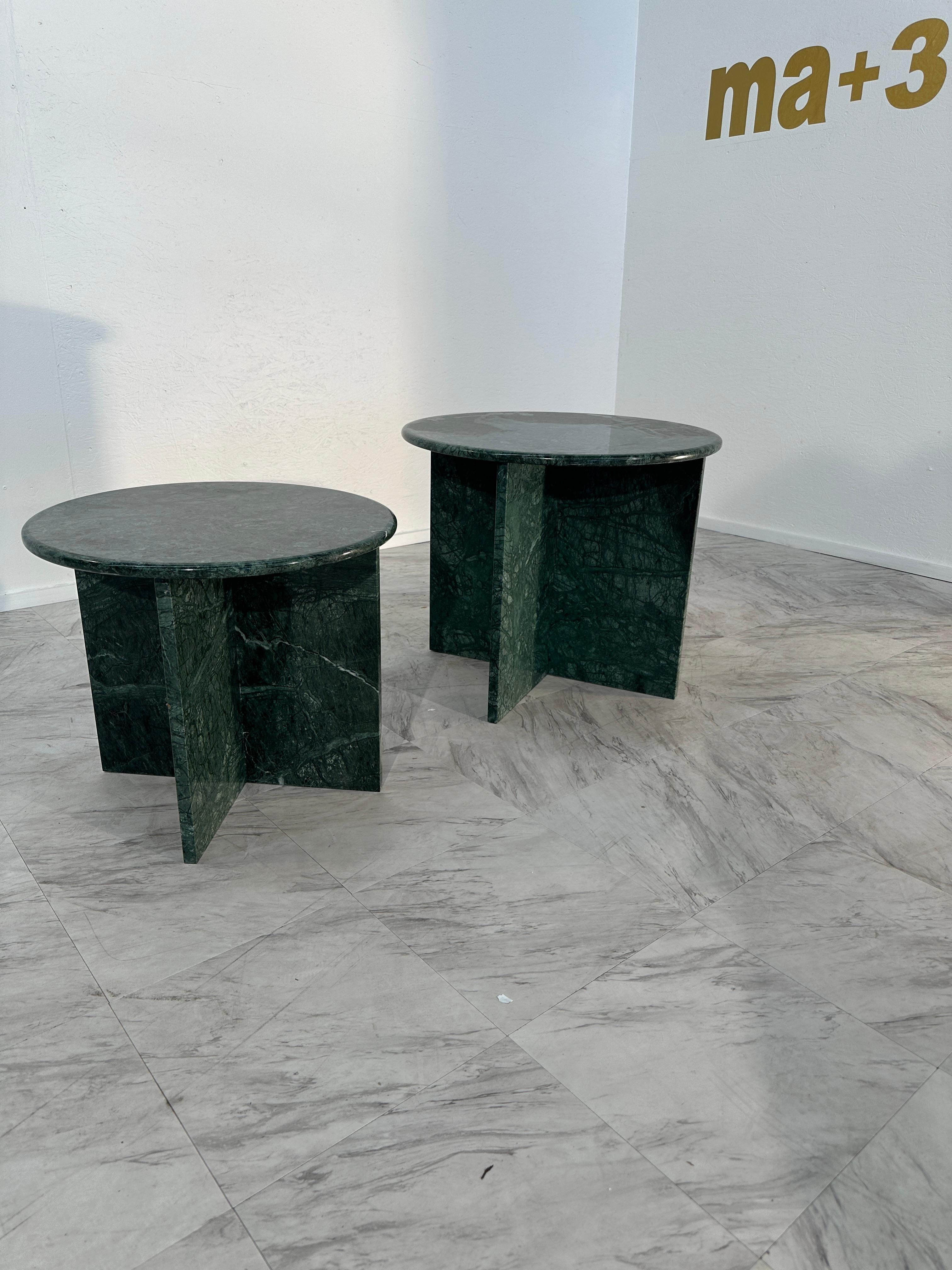 The Pair of 2 Italian Green Marble Side Tables from the 1980s features a distinctive design with a fully green marble base and round green marble tops. The elegant and timeless pieces showcase the beauty of Italian craftsmanship, combining a sleek