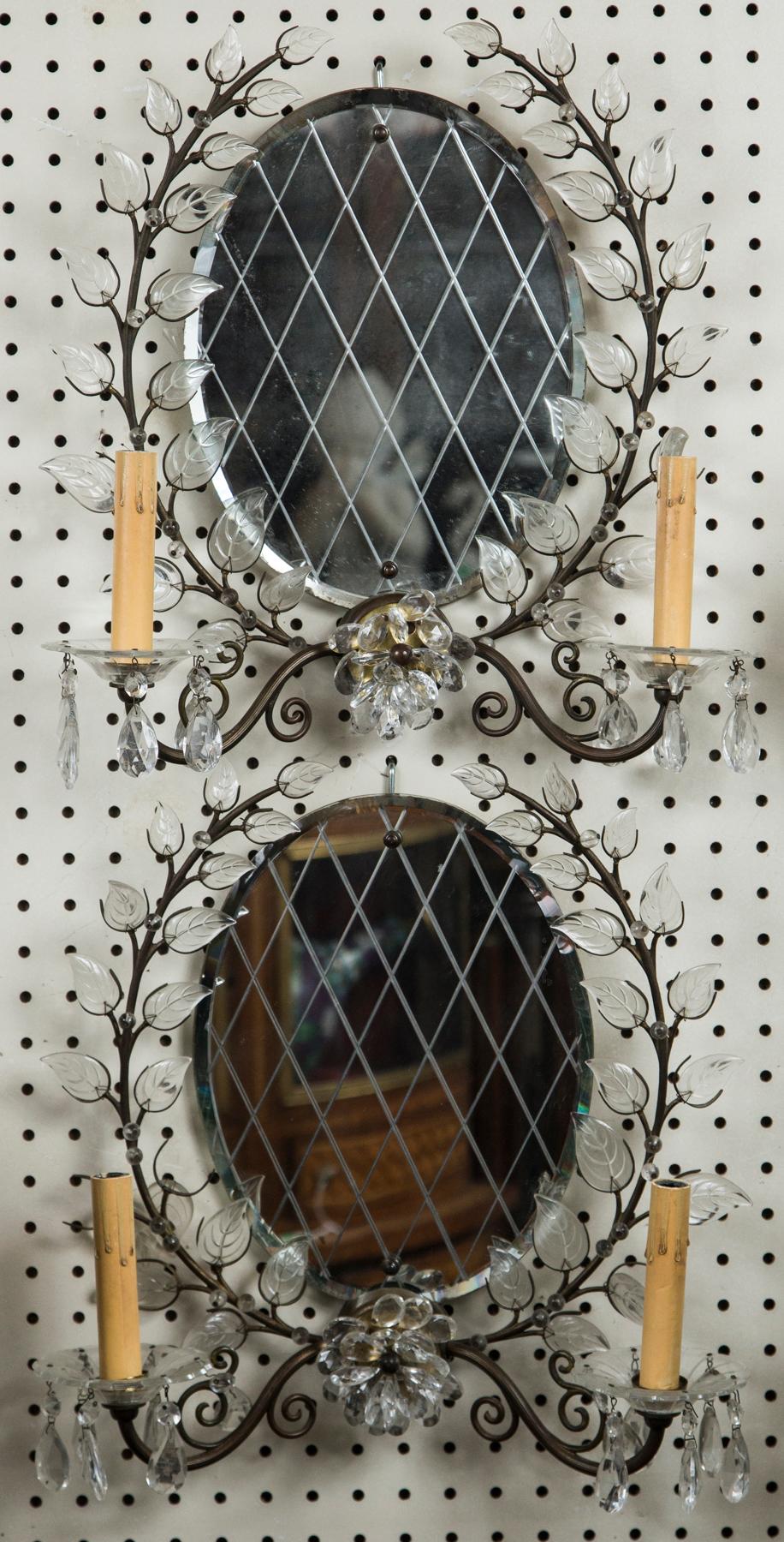 Oval beveled edge glass with cross hatching. Surrounded by laurel leaf forms on stems with small glass beads, mounted with wire attached to the separated metal arms on either side, at the central flower. Scrolling metal arms with glass baubeches and