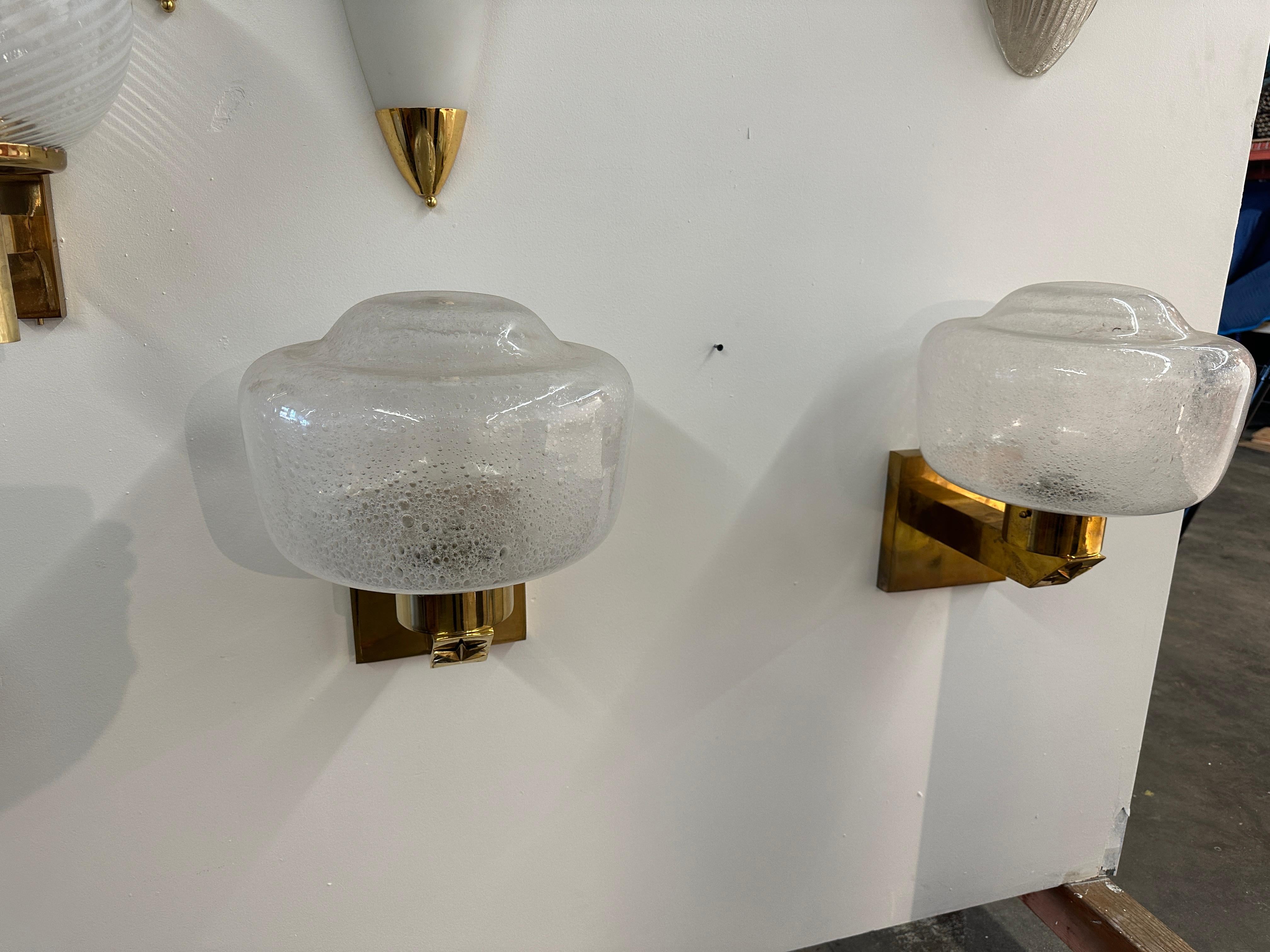 The Pair of 2 Mid Century Italian Wall Sconces from the 1970s exude a classic and sophisticated design. Featuring a brass frame, these wall sconces showcase the enduring charm of mid-century aesthetics. The brass material adds a touch of warmth and
