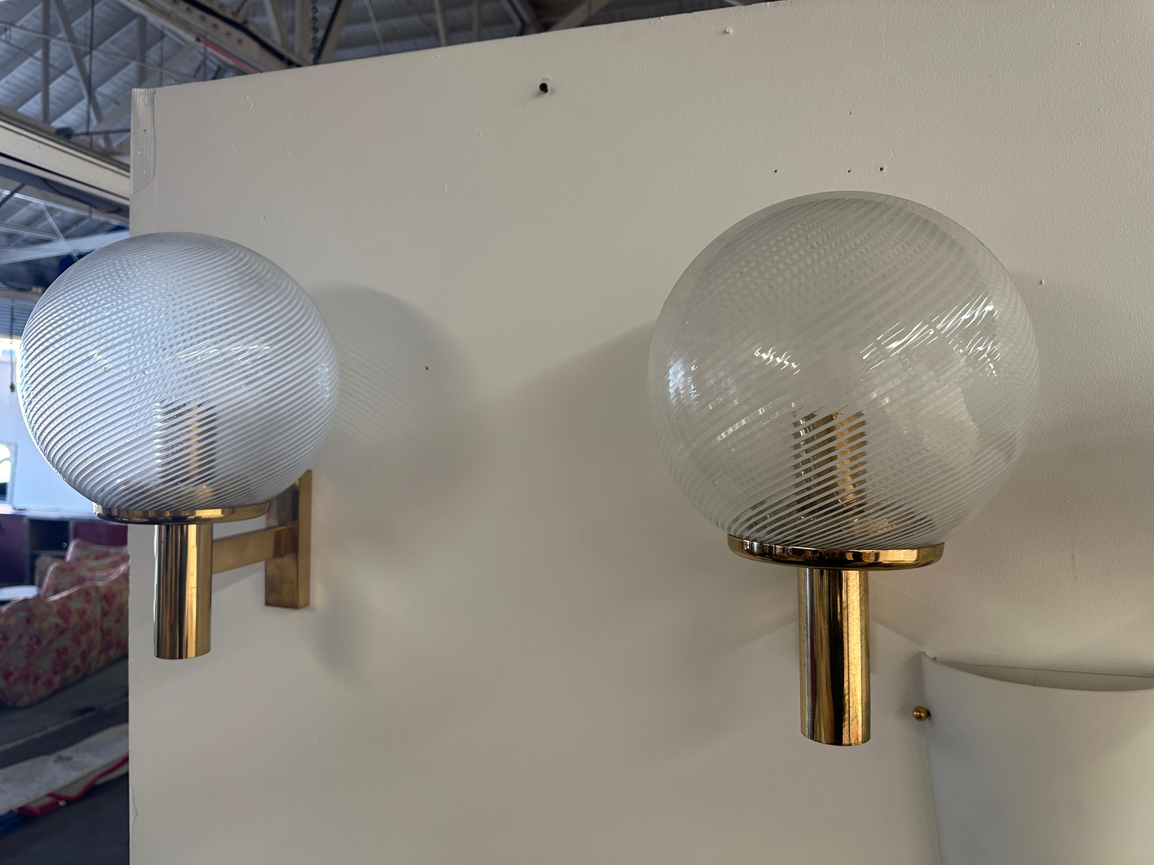 The Pair of 2 Mid Century Italian Wall Sconces from the 1970s exude a timeless and elegant design. Featuring a fully brass frame, these wall sconces capture the essence of mid-century aesthetics with their sleek and sophisticated appearance. The