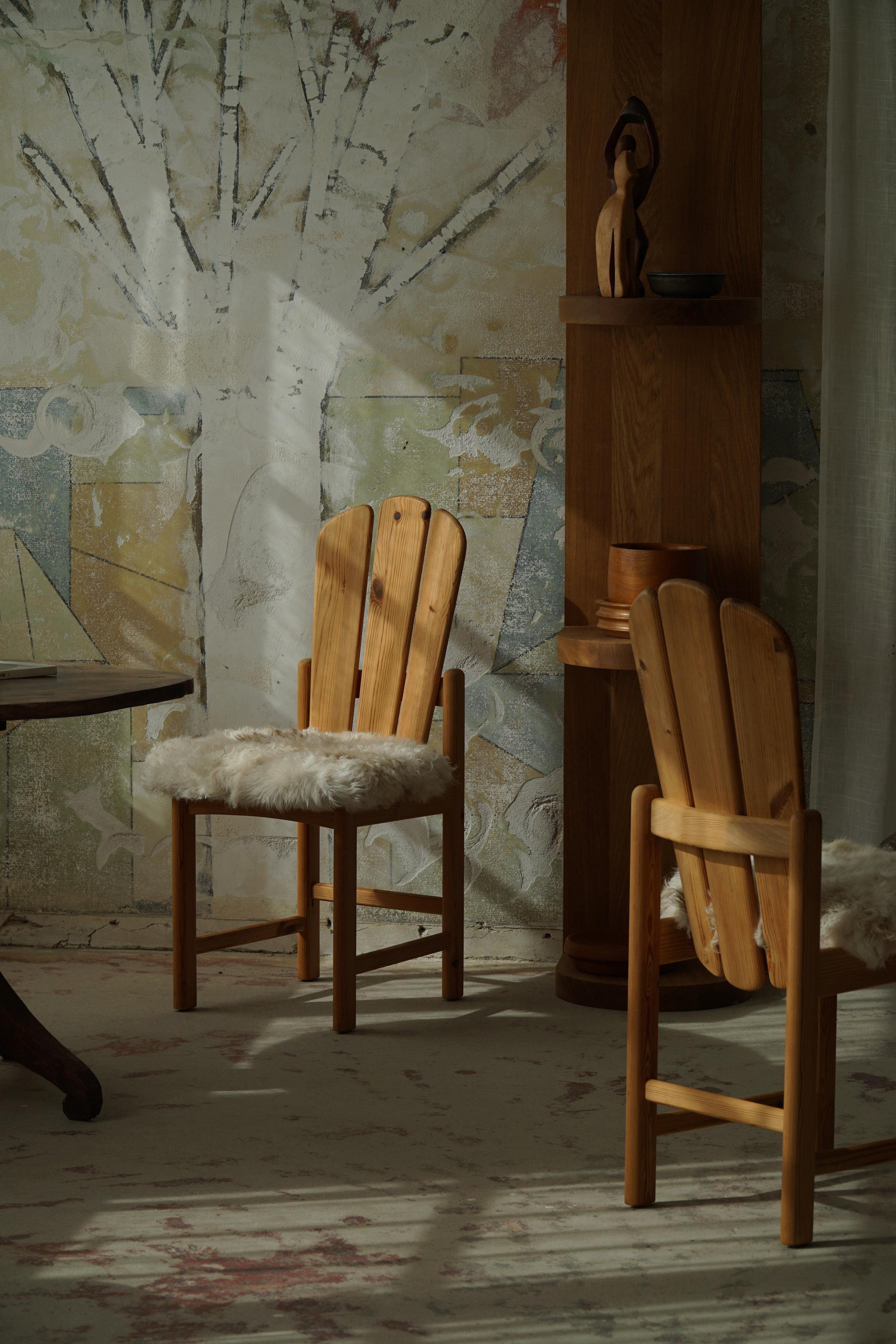 Paire de chaises de salle à manger sculpturales en pin massif et assise rembourrée en laine d'agneau. Fabriqué par un ébéniste danois dans les années 1970. Ces chaises donnent une impression très forte qui se marie bien avec de nombreux types de