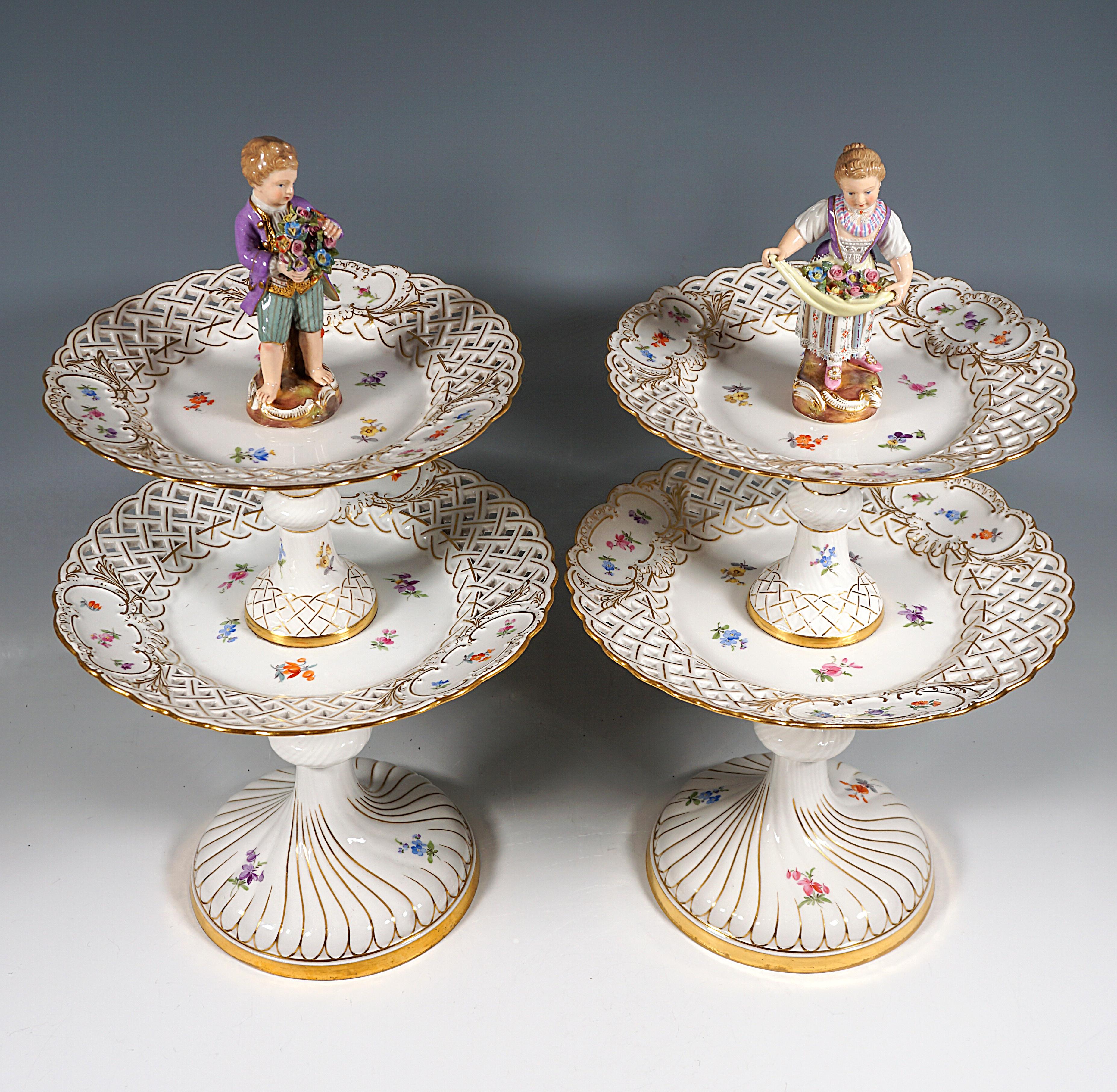 Pair of delicate porcelain centrepieces on a high, round base with curved boss decoration, the shaft divided by bead-like extensions, above two tiers in the form of two differently sized breakthrough plates with medallions, each crowned by a