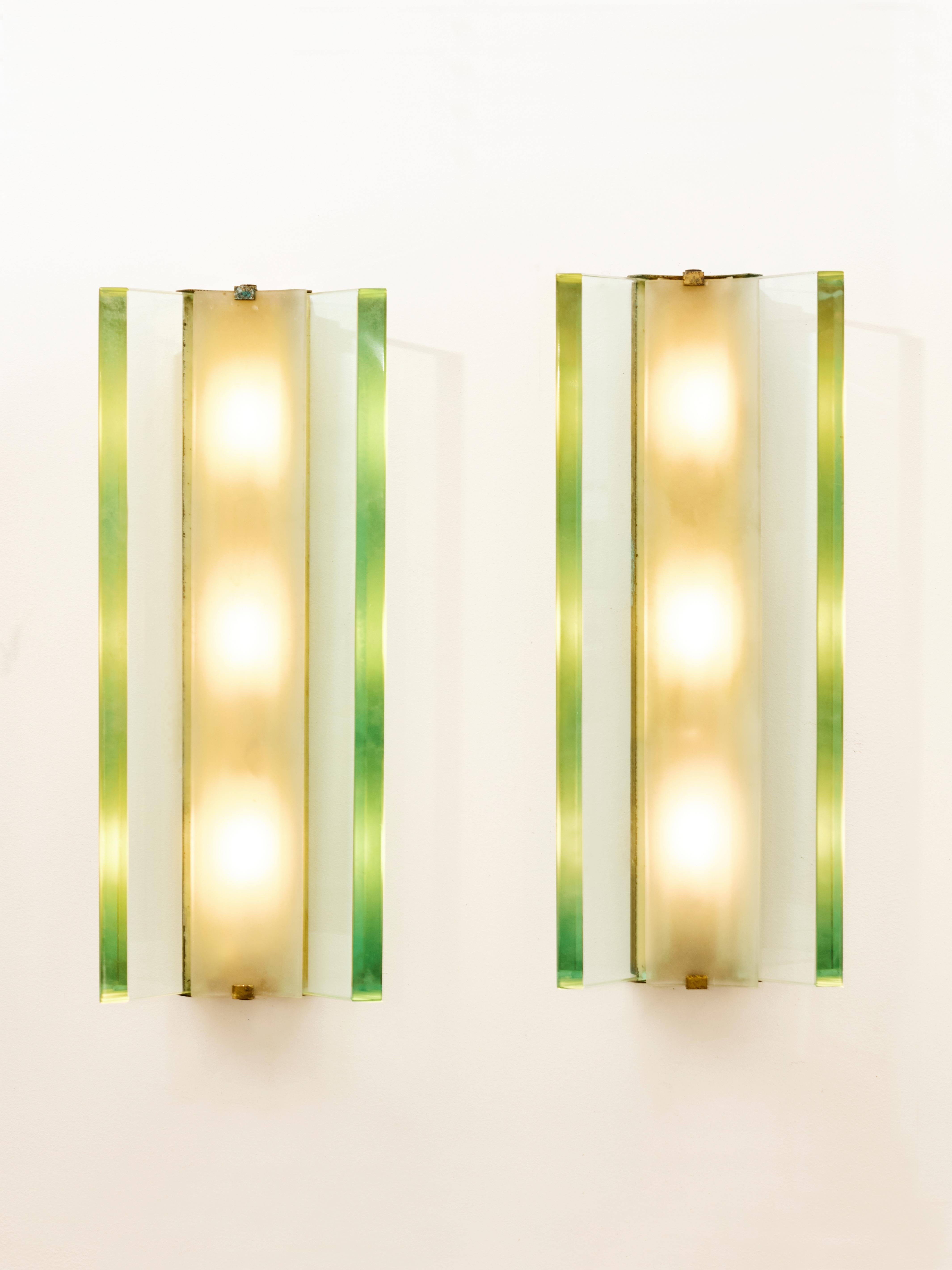 Pair of sconces model 2052, designed by Max Ingrand circa 1960 for Fontana Arte. Each features a brass rectangular structure and a combination of three clear beveled and frosted glass panels.
Each sconce has three inner bulbs which light gets