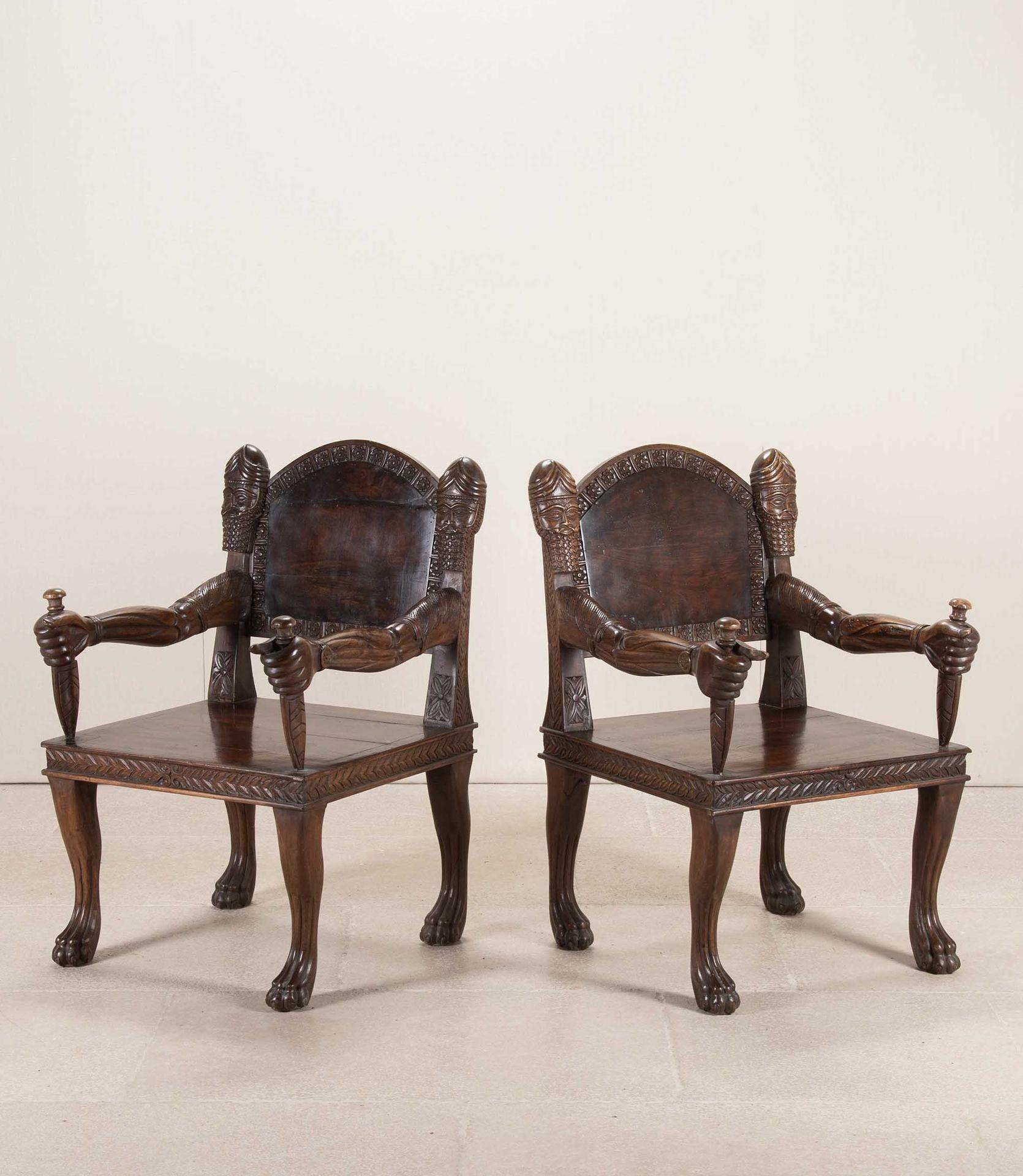 Paire de fauteuils ouverts du 20e siècle, de style anglo-indien, sculptés en forme de trône. 
Le bois est très lourd et a un aspect très particulier. Les bras de la chaise sont sculptés comme de véritables bras tenant une dague qui est le support de