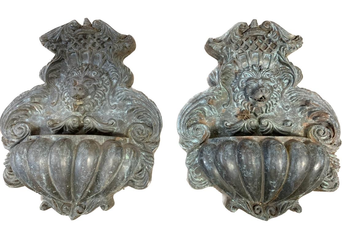 Pair of well patinated bronze lion head wall fountains with melon form basins. The fountains having well cast dimensional lion heads below a pediment with lattice and foliate motifs.
The back with hanging brackets.
Dimensions: 15