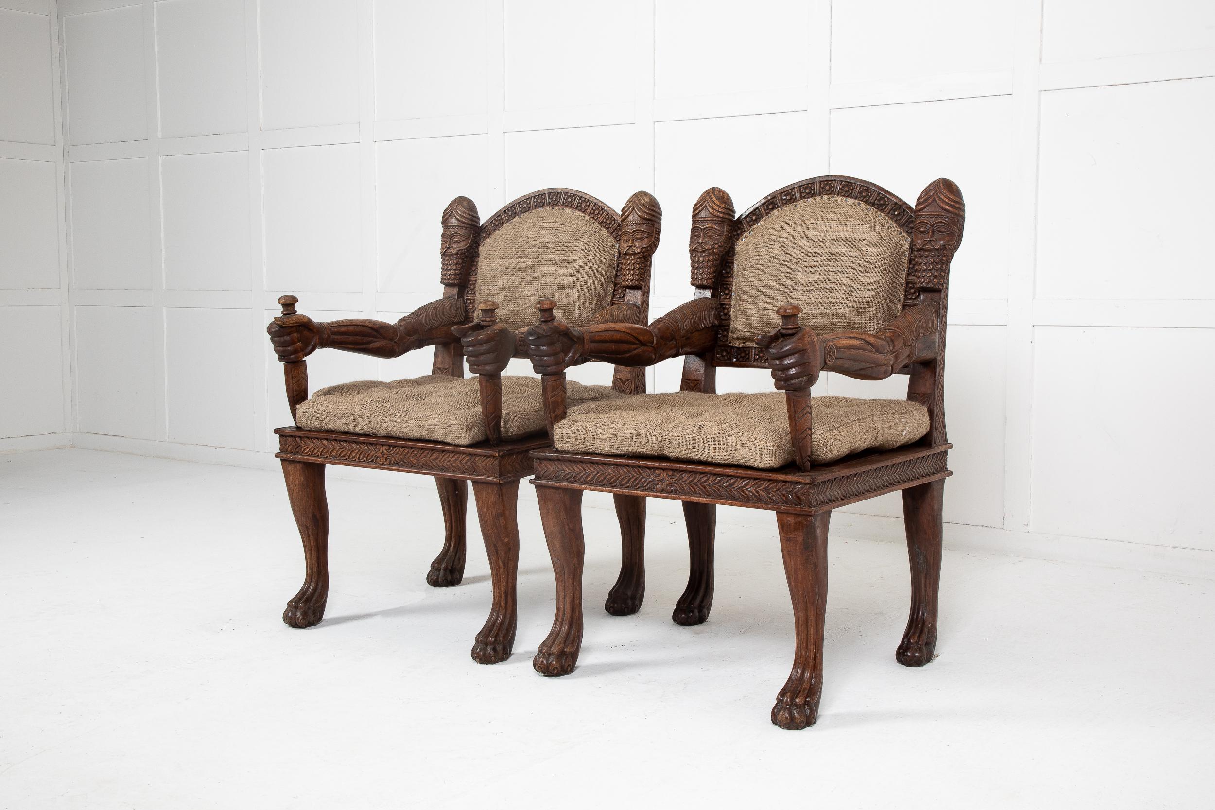A pair of unique, late 20th century armchairs, possibly Asian. The large, sturdy and comfortable armchairs are very unusual, and carved with elaborate details which catch the eye and have plenty of character. The arms are of human form, gripping