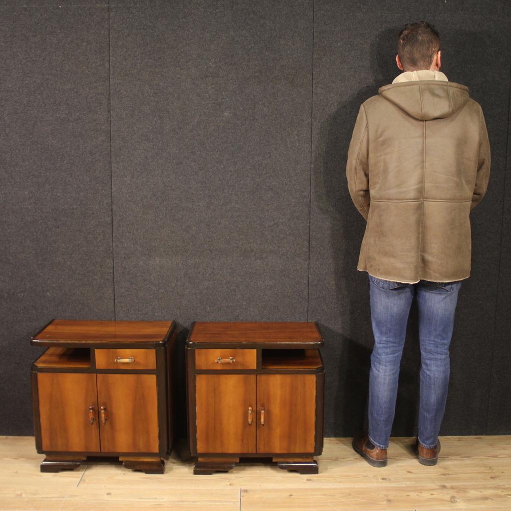 Pair of Italian bedside tables from the mid-20th century. Furniture carved and veneered in walnut, mahogany and fruitwood in Art Deco style. Bedside tables equipped with two doors, a drawer placed at the same height as a magazine shelf and an upper