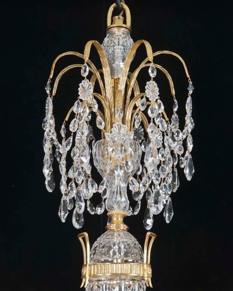 Une paire de lustres à douze lumières de belle qualité dans le style de Perry & Co. Le fût en cristal taillé et monté en bronze doré est centré par une urne montée en bronze doré et surmontée d'un double palmier suspendu en bronze doré. La plaque de