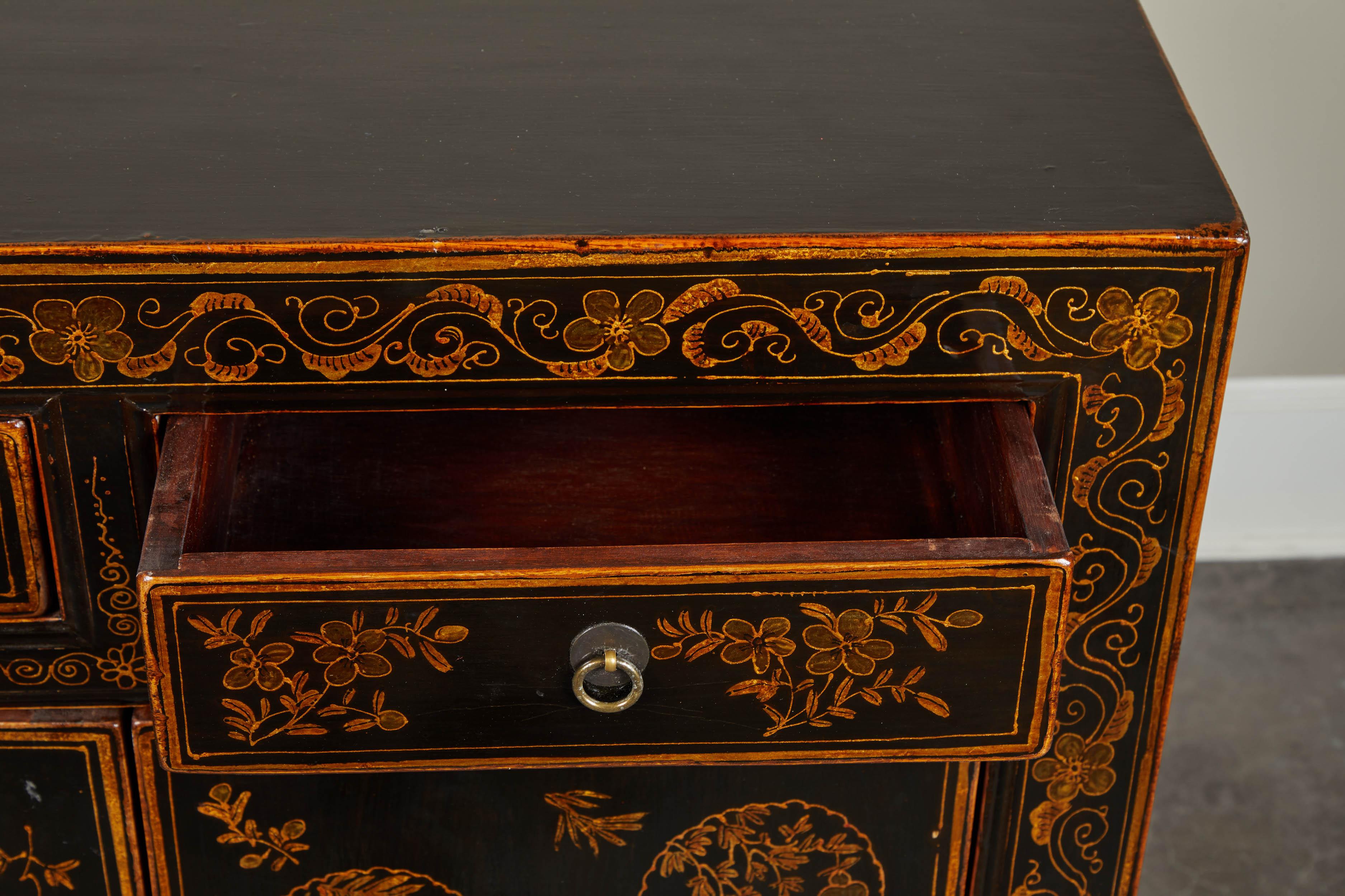 Pair of black lacquer side cabinets featuring gold painted chinoiserie details throughout. Pair of simple hinge doors and single drawer on top, circa 20th century.
