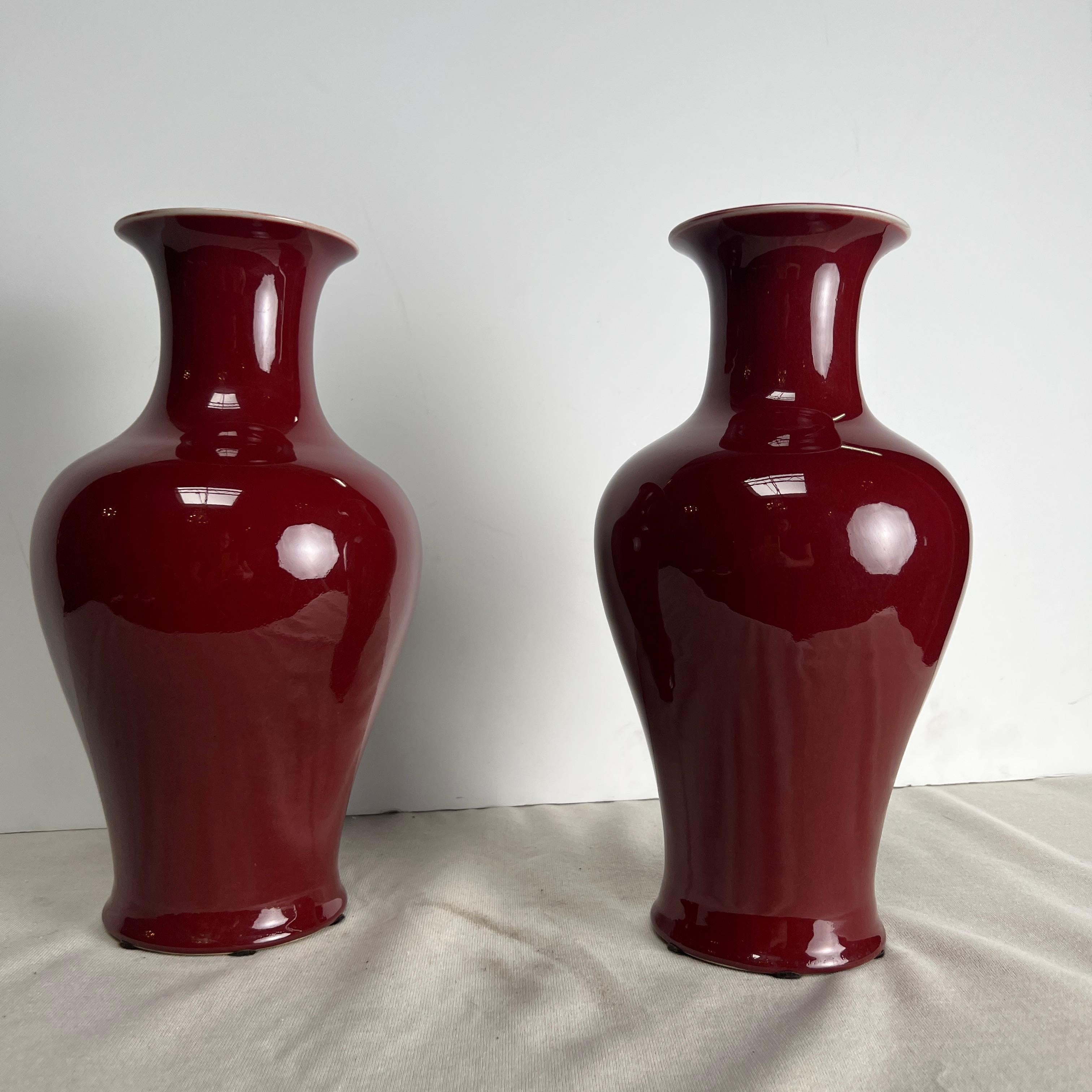 A pair of Chinese porcelain vases with an oxblood, red, sang de boeuf glaze. These large vases are very decorative and would make a great pair of lamps or vases.  