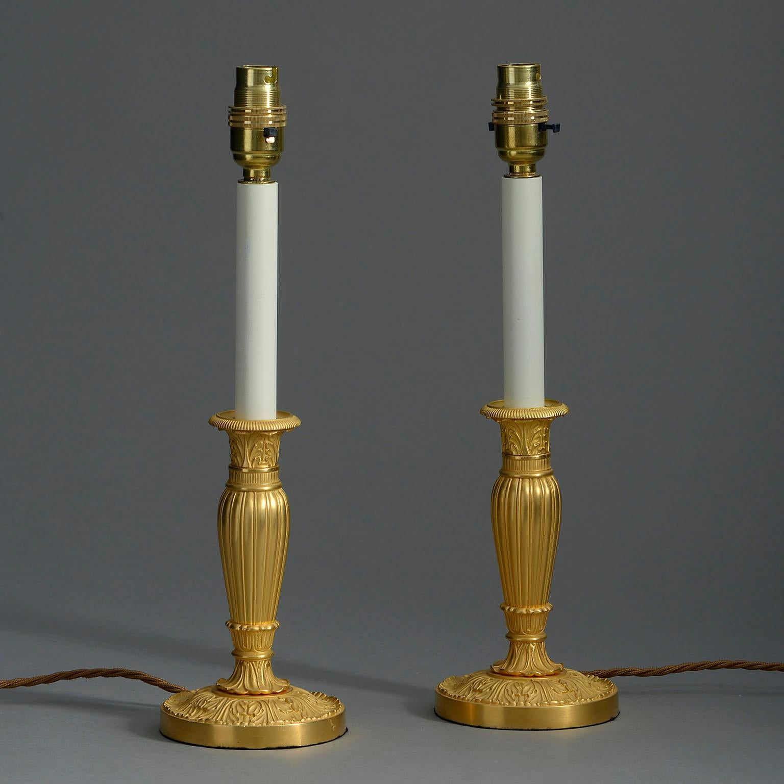 A pair of twentieth century ormolu candlesticks with foliate casting and mounted as lamps.

Height includes painted candle stems.

Wired to UK standards. This pair of lamps can be rewired to all international specifications.

Shades available