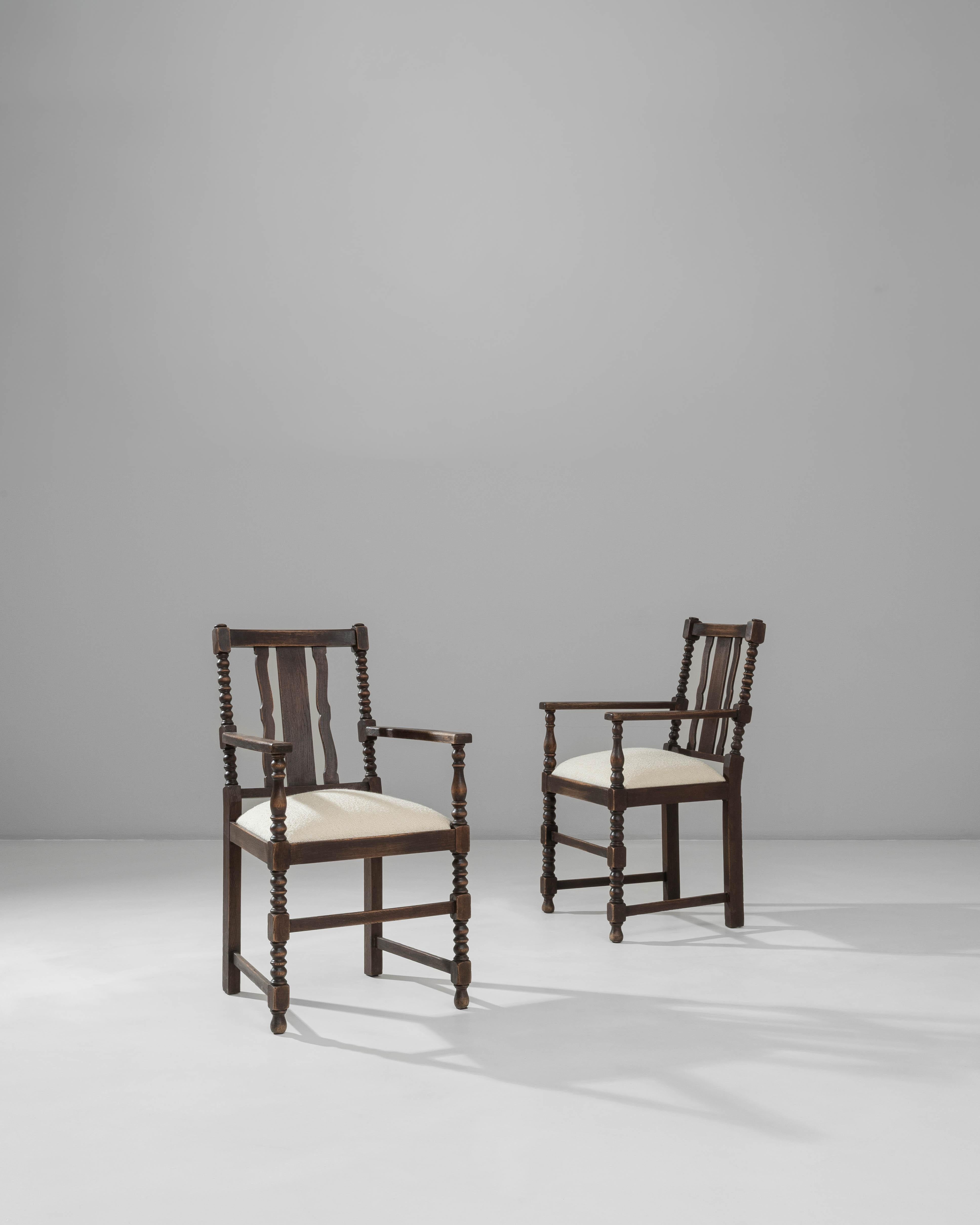 Cette paire de fauteuils en bois de style baroque français du XXe siècle témoigne de la qualité de l'artisanat et des détails sculpturaux associés à ce style. Chaque chaise est dotée de pieds, de brancards et de supports d'accoudoirs tournés qui