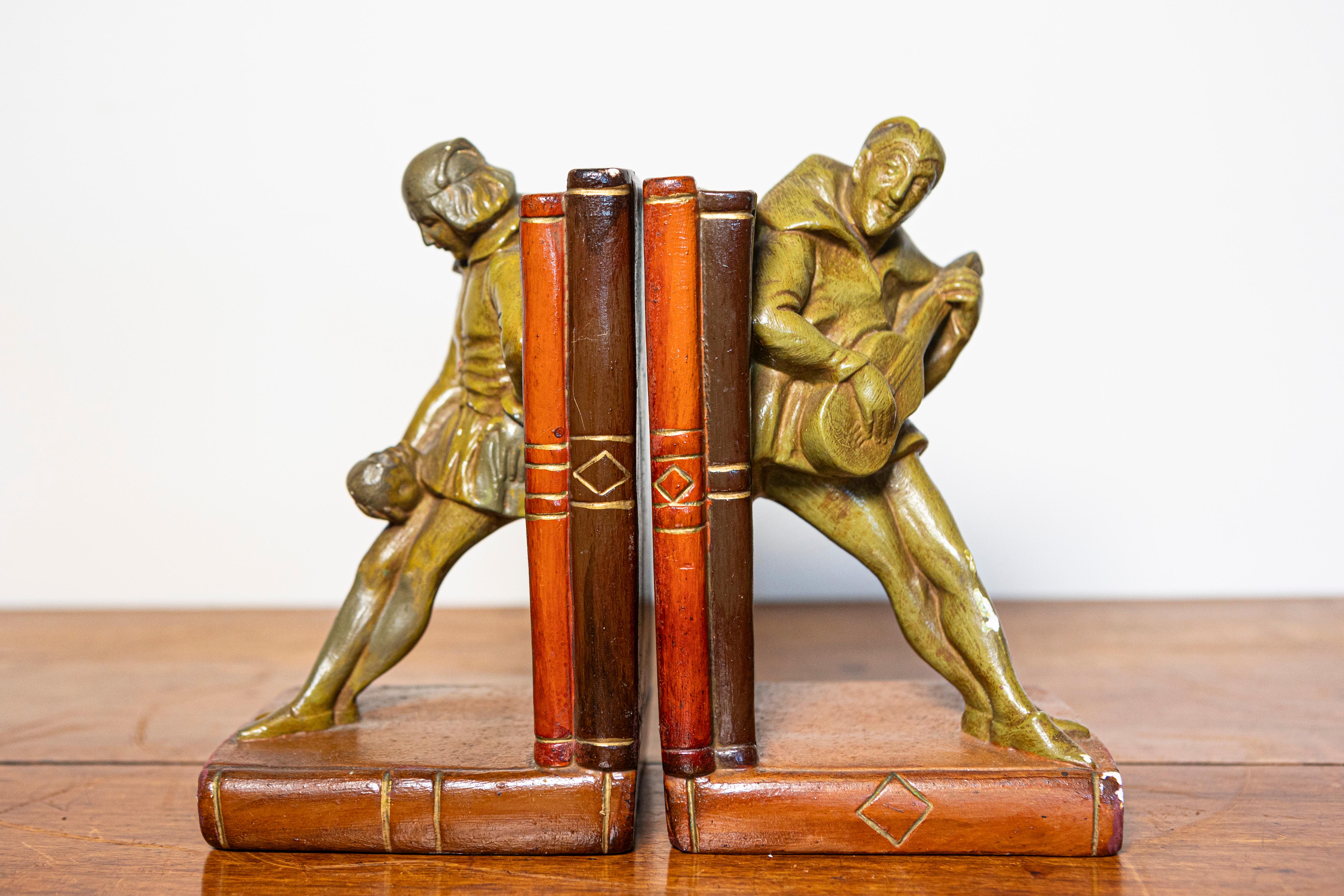 This charming pair of 20th-century French bookends brings a delightful touch of artistry and whimsy to any bookshelf. Each bookend features a finely cast bronze figure, one depicting a jovial lute player and the other a playful jester, both dressed