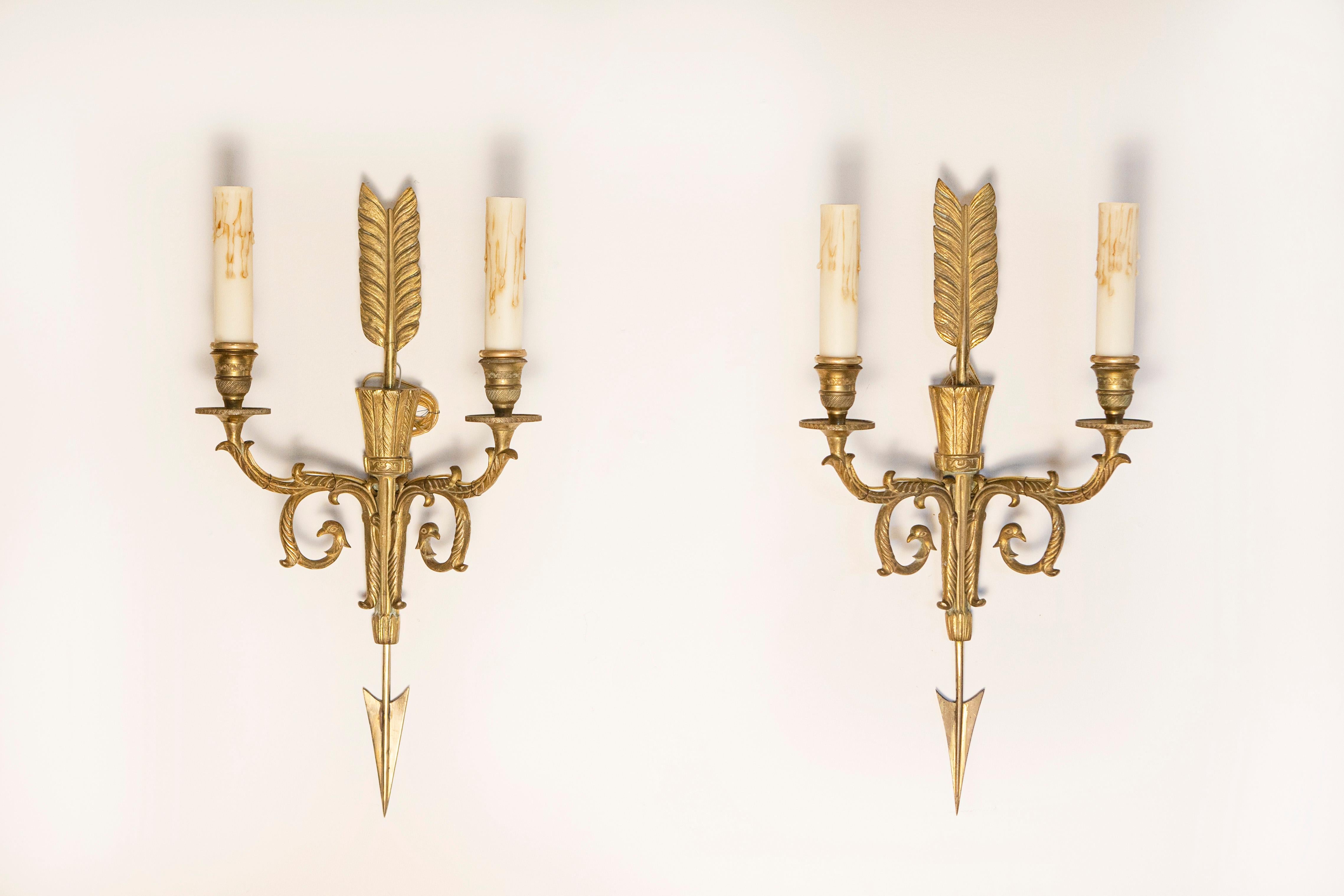 Une exquise paire d'appliques françaises en bronze du 20e siècle, fabriquées dans le style Empire Revival, incarnant l'élégance et la grandeur synonymes de l'art décoratif français. Ces appliques finement détaillées sont méticuleusement coulées dans