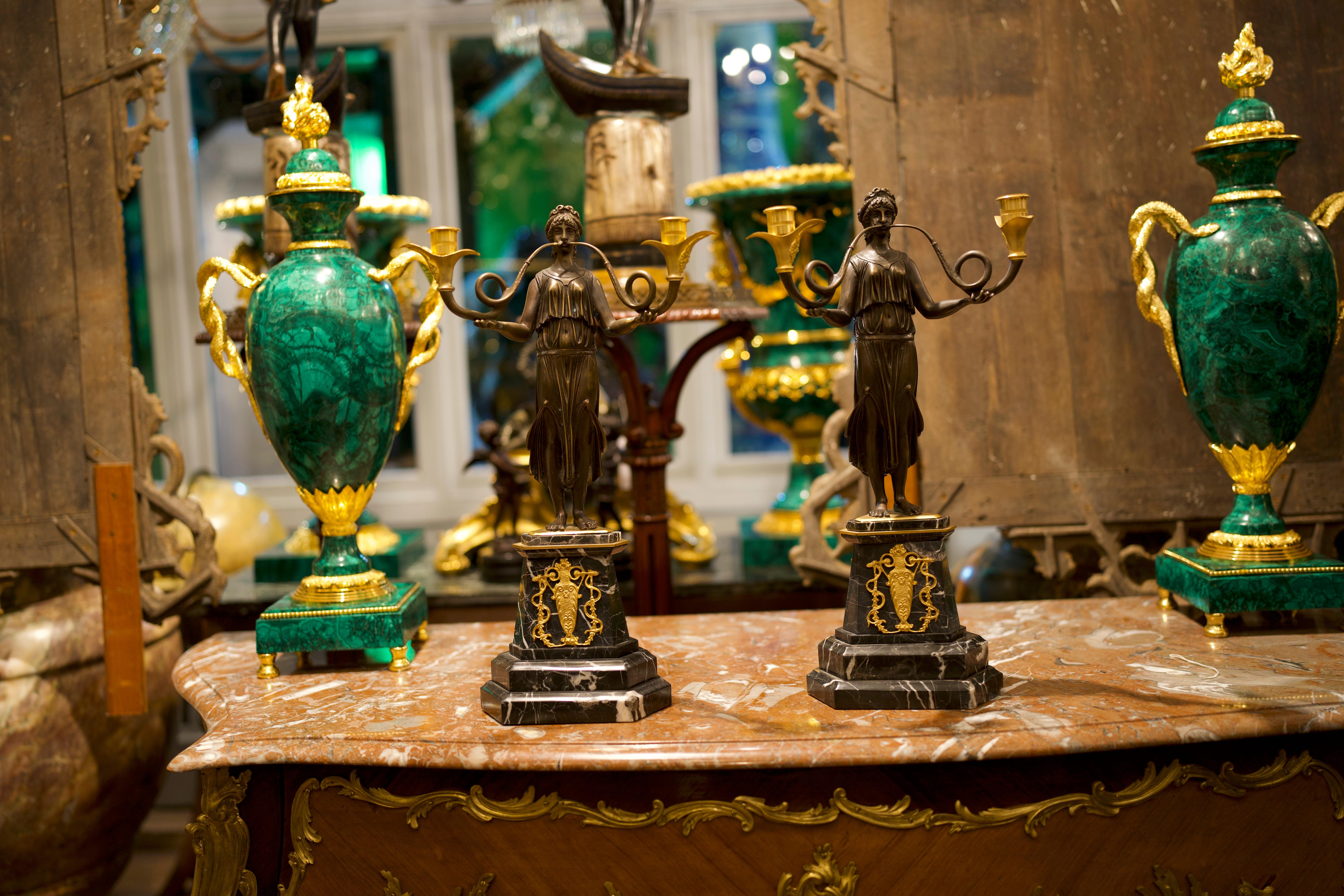 Pair of 20th century French gilt and bronze candelabra of the Empire style.

Constructed in two colour gilt and patinated bronze; the feminine Grecian figures draped with diaphanous robes blowing bi-form trumpets of swept form, terminating in
