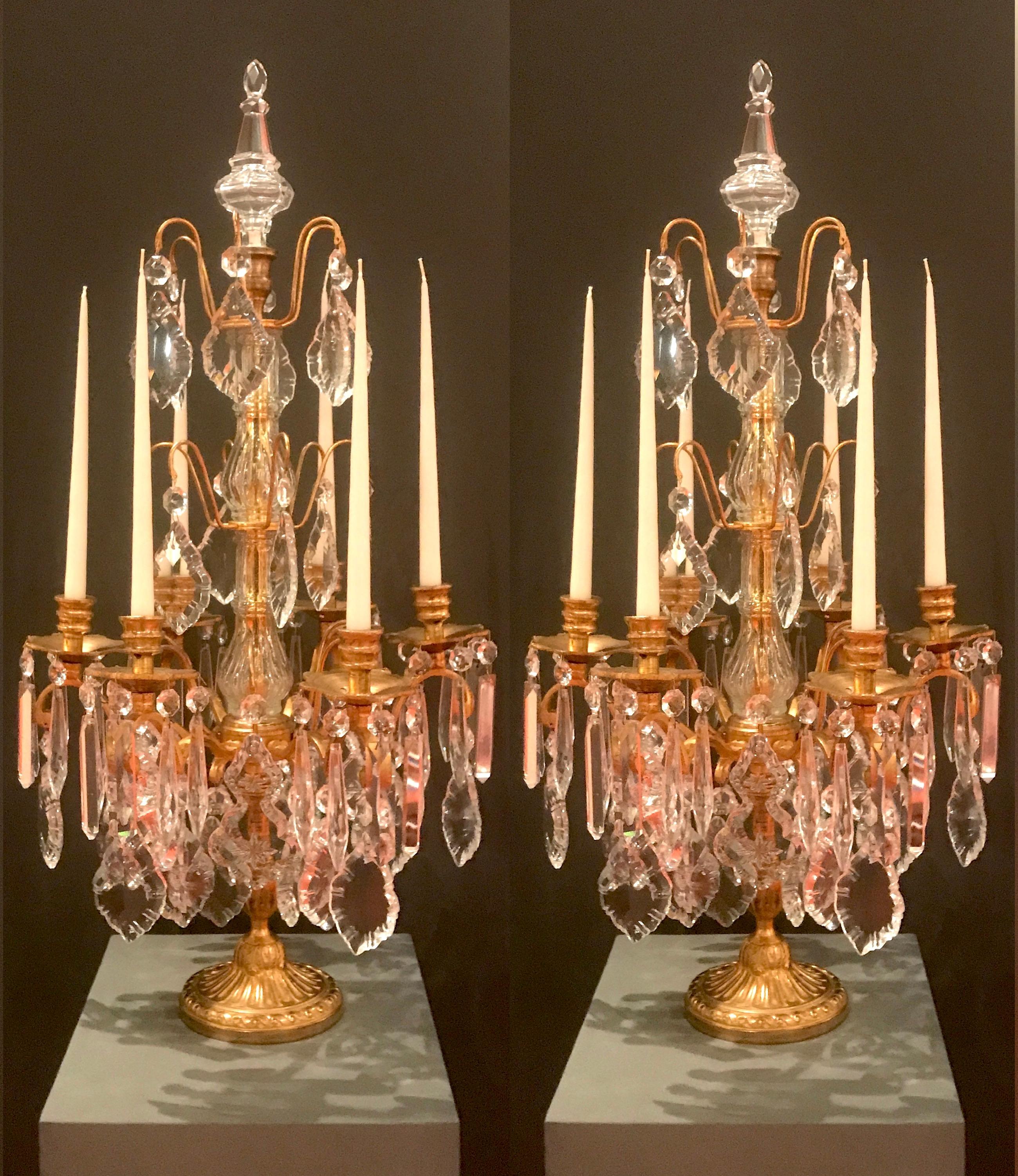 A charming pair of six-armed gilt bronze and crystal candelabra, of French origin, in good condition.
Each ormolu  flambeau has six curved branches, the frame is decorated by fan shaped and prism crystal pendants, as well as the central stem coated