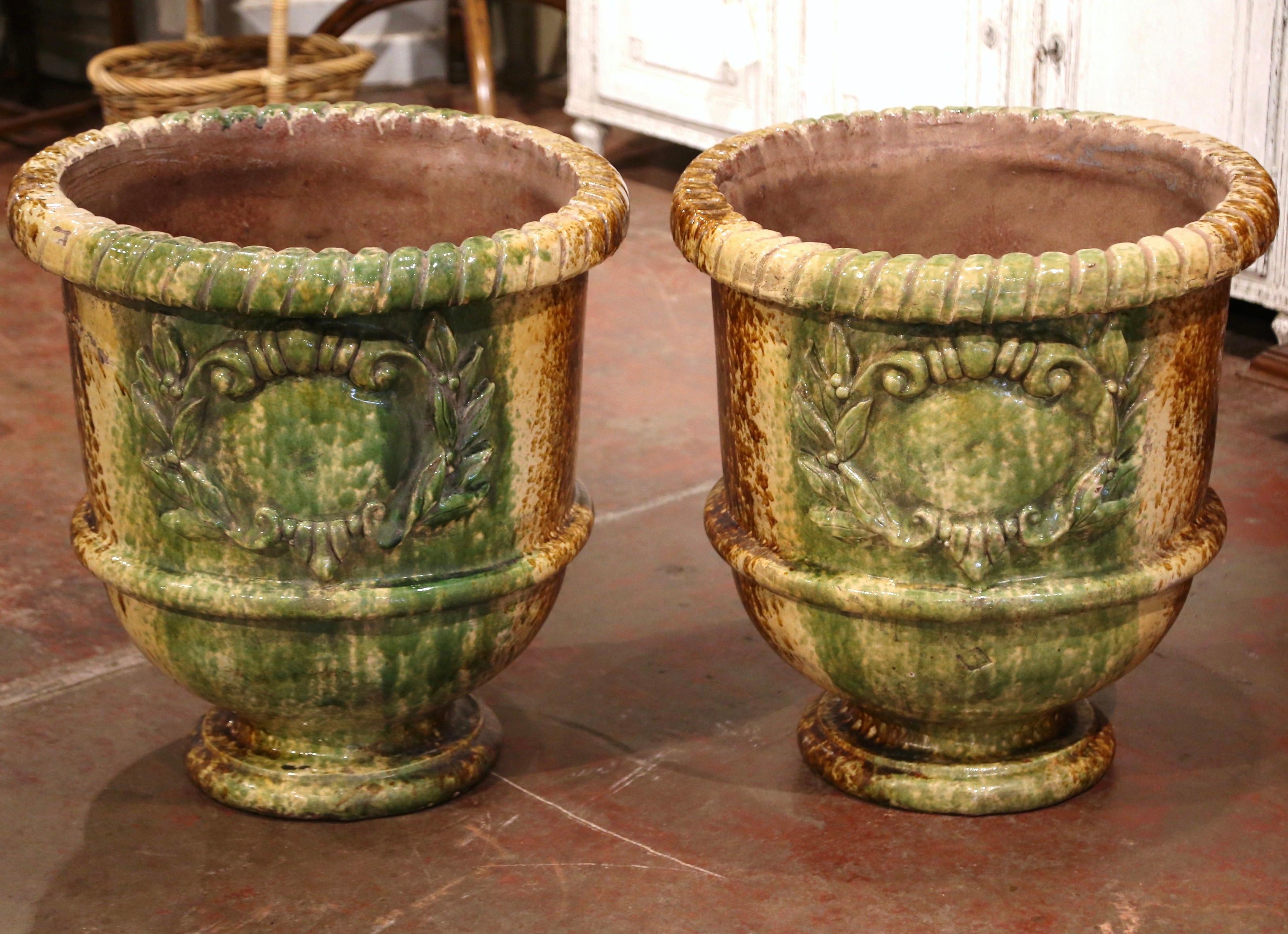These large, colorful pots were created near Anduze, France, circa 1990. Each classic earthenware planter features carved decor with a glazed finish in the Provençal green and mustard finish. The important pots are in excellent condition with a rich