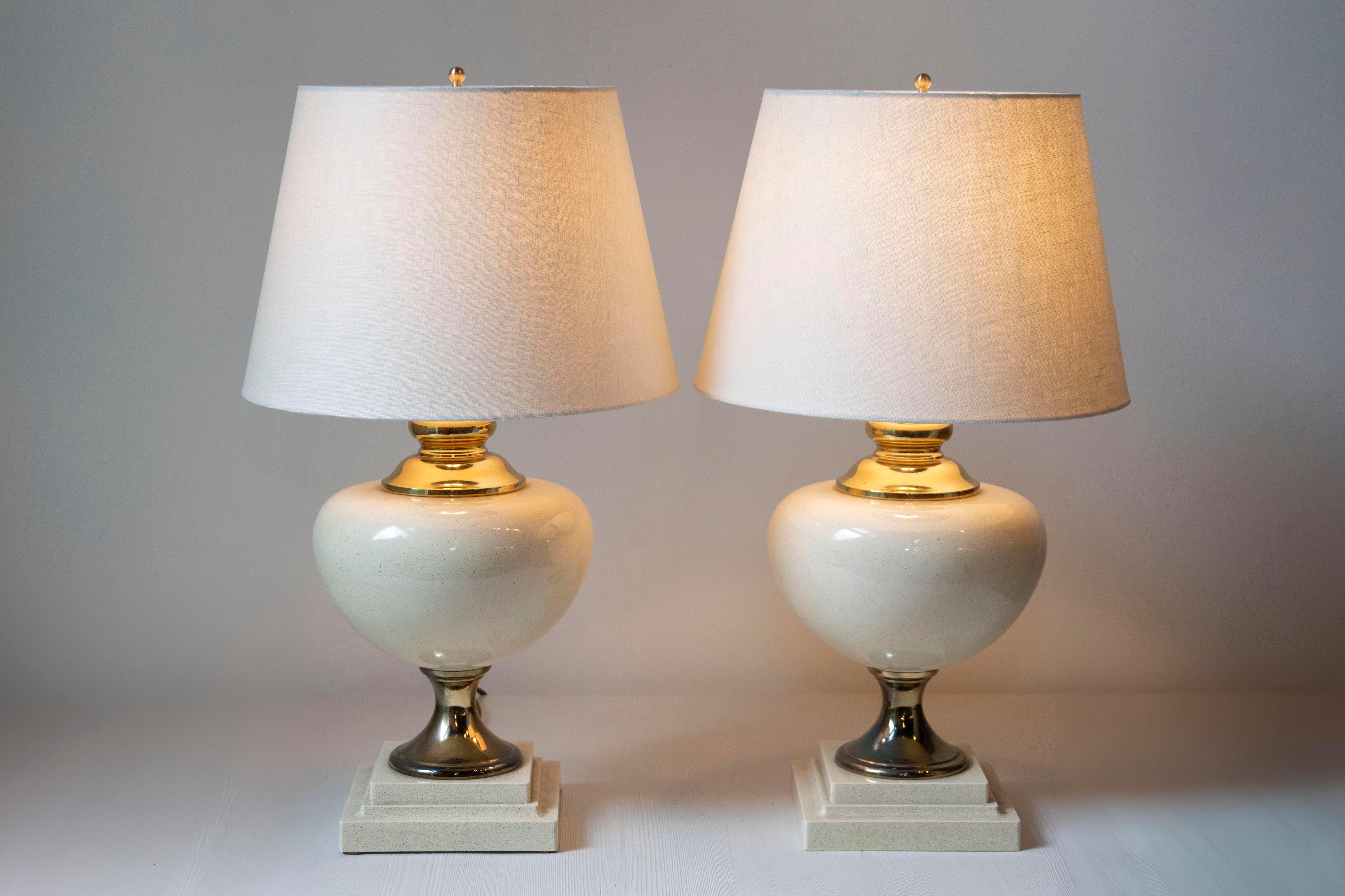 Cette élégante paire de lampes françaises du XXe siècle reflète une sophistication intemporelle et une polyvalence moderne. Les lampes présentent des bases gracieusement arrondies fabriquées en céramique brillante dans un ton ivoire doux, ce qui