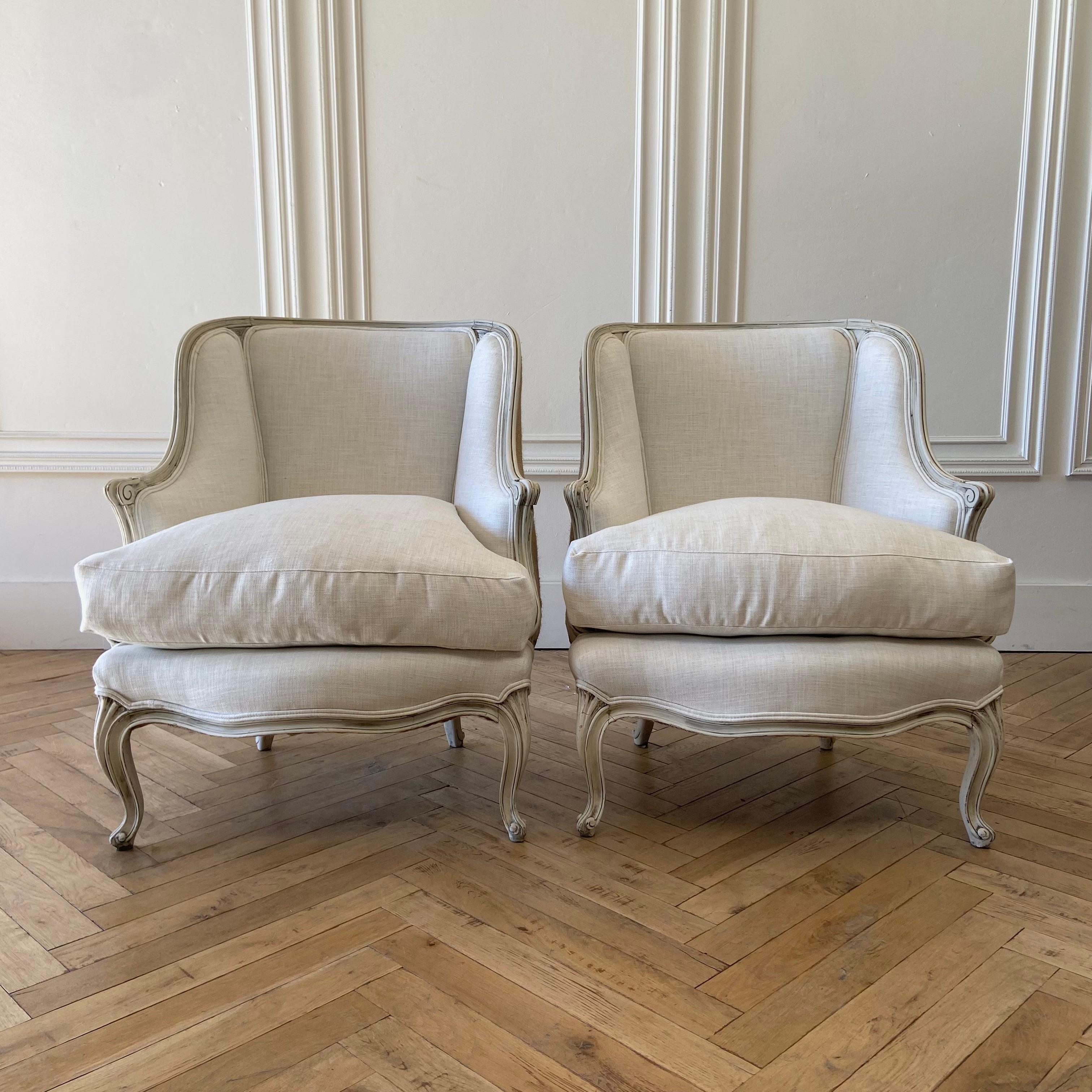 Pair of Vintage Bergere chairs in the Louis XV Style.
Oyster white painted finish, with subtle distressed edges, with antique glazed patina.
Upholstery is in a natural linen blend herringbone, with down wrapped seat cushions. Solid and sturdy