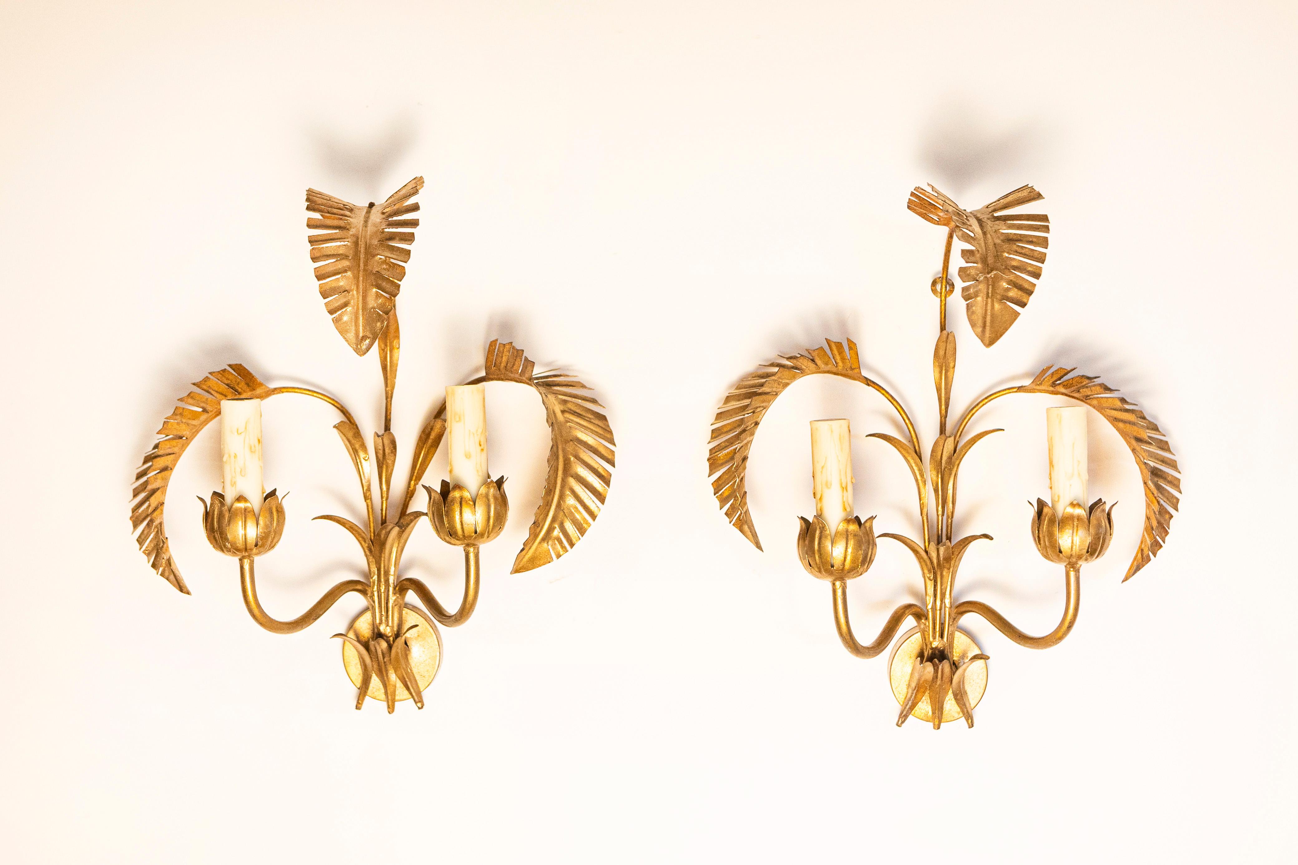 Cette exquise paire d'appliques françaises du XXe siècle - inspirée par la Maison Jansen - présente l'élégance intemporelle et le design audacieux synonymes de la célèbre maison de design. Fabriquées en métal doré, ces appliques présentent un motif