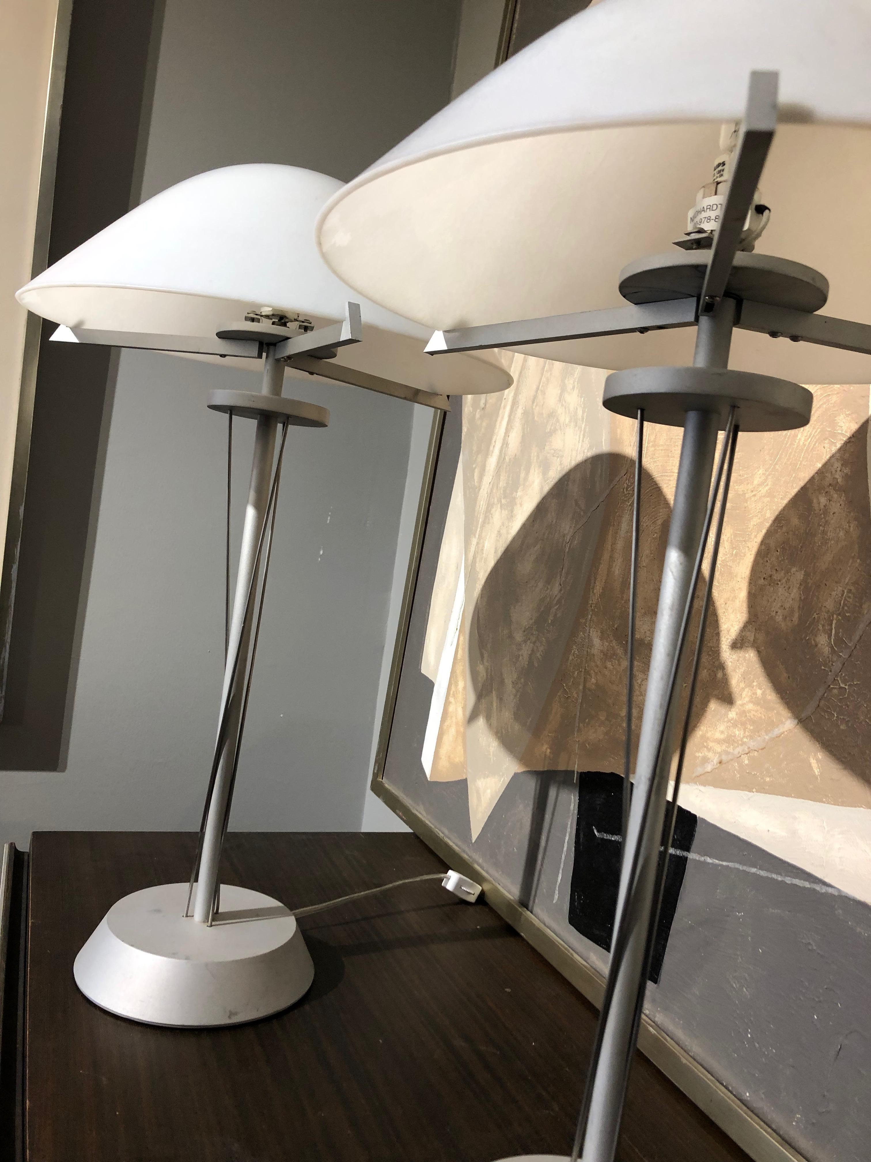 Pair of 20th Century German Postmodern steel lamps with white milk glass shades.
A sleek and interesting addition to any room. Made of brushed steel with milk glass shades that have a beautiful pearlescent sheen. One shade has a small chip and
