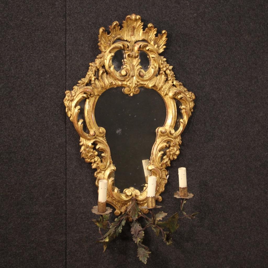 Pair of Venetian mirrors from the mid-20th century. Finely carved and gilded wooden furniture, hand painted metal decoration and arms for the lights (see photo). Pair of wall lights equipped with three electrified lights (each). Electrical system