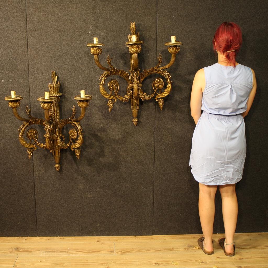 A pair of mid-20th-century French wall lamps. Exceptional size and quality, crafted from gilded and chiseled bronze in the Louis XVI style. A three-light wall lamp of considerable weight (approximately 30-40 kg each), it has to be mounted on the