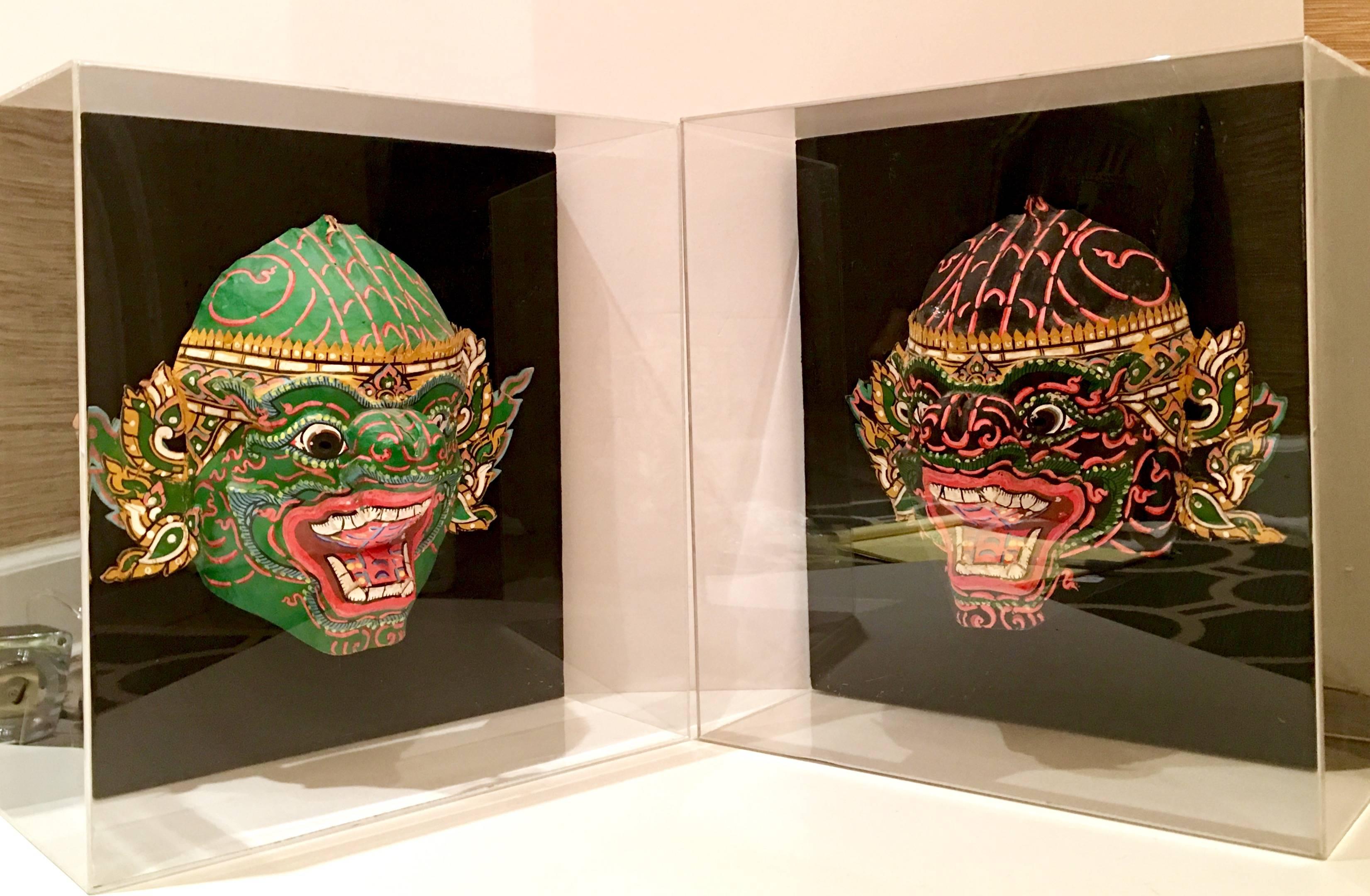 Fantastic pair of Vintage Javanese paper mâché hand-painted Tribal celebration masks. Each mask is mounted on black linen in large Lucite shadow box frames. Each mask measures approximately, 11