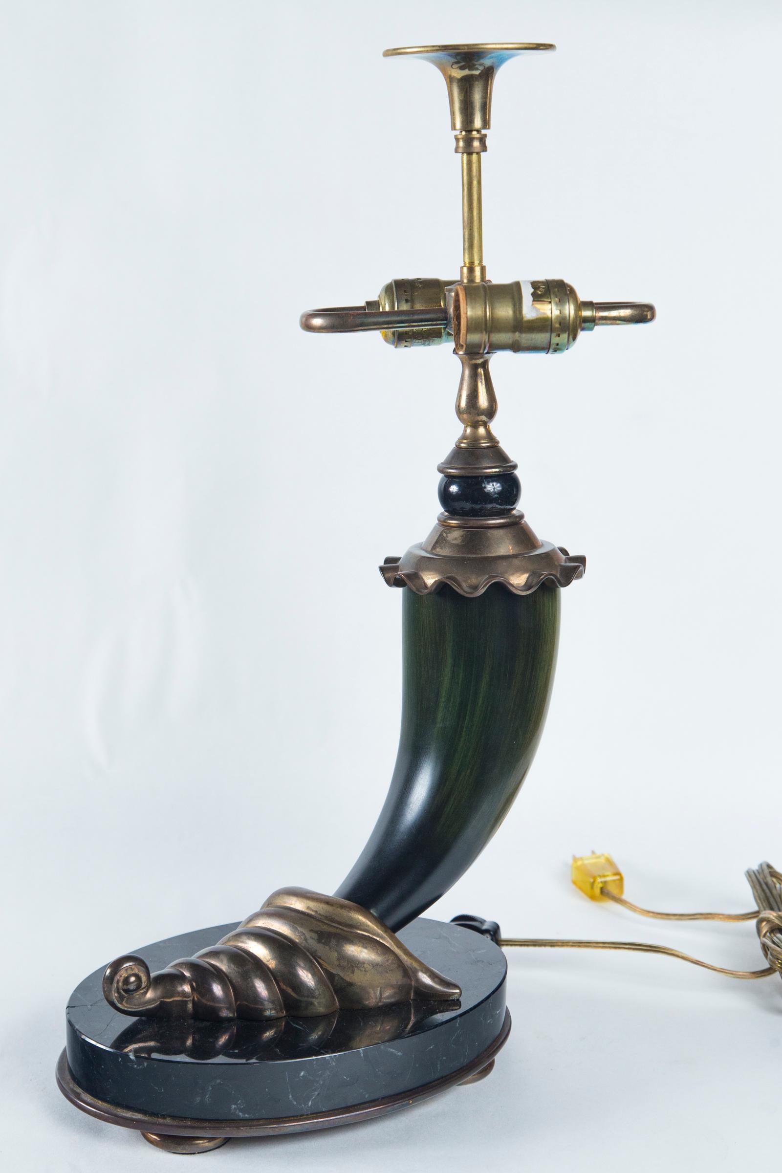 A polished black marble base sits atop a thin brass oval plate with bun feet.
Polished dark animal horn, probably from a steer, with a cornucopia designed tip cap sits upon the marble. At the top of the horn is a brass disc from where the S-form