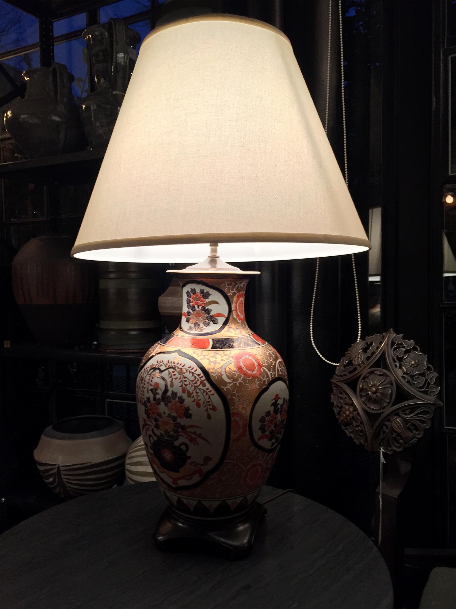 These 20th century porcelain lamps are in the Imari ware style, which, in turn, is influenced by the bold colors of Arati ware from Japan. This pair is comprised of hand-painted porcelain bodies in a palette of white, deep indigo blue, red-orange,