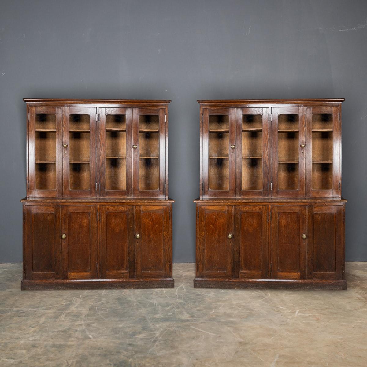 Antique early 20th Century delightful English oak and glass fronted bookcases / cabinets, featuring closed cupboard bases. Adorned with original brass handles, these cabinets exude timeless elegance. Whether for a home library or as furniture for