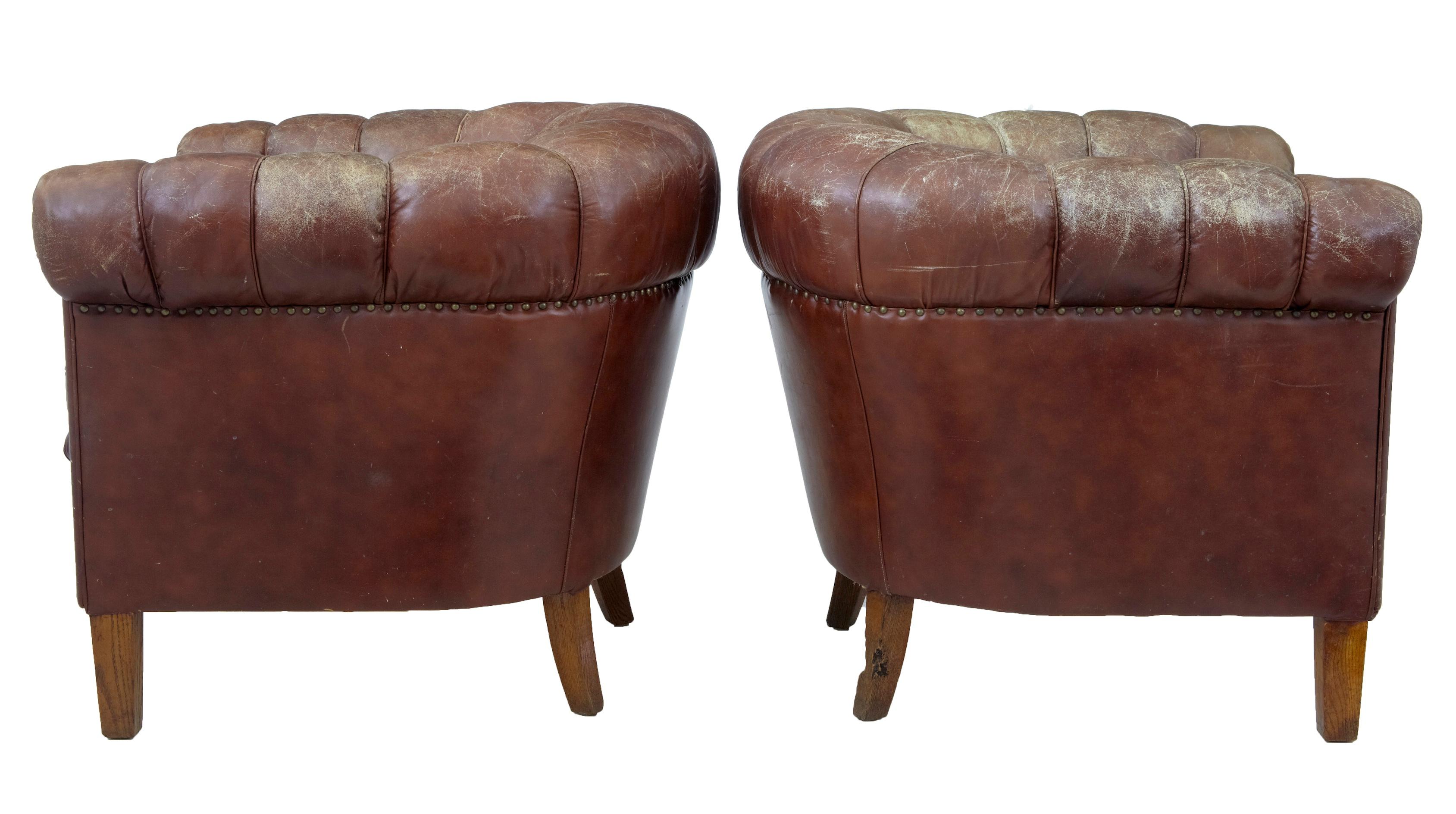 Comfortable pair of 1920s leather button back armchairs.
Over stuffed roll top arms, with separate seat cushion.
Standing on oak legs.
Some splits and marks to leather, one back leg appears to have been a favourite for a pet and is currently abit