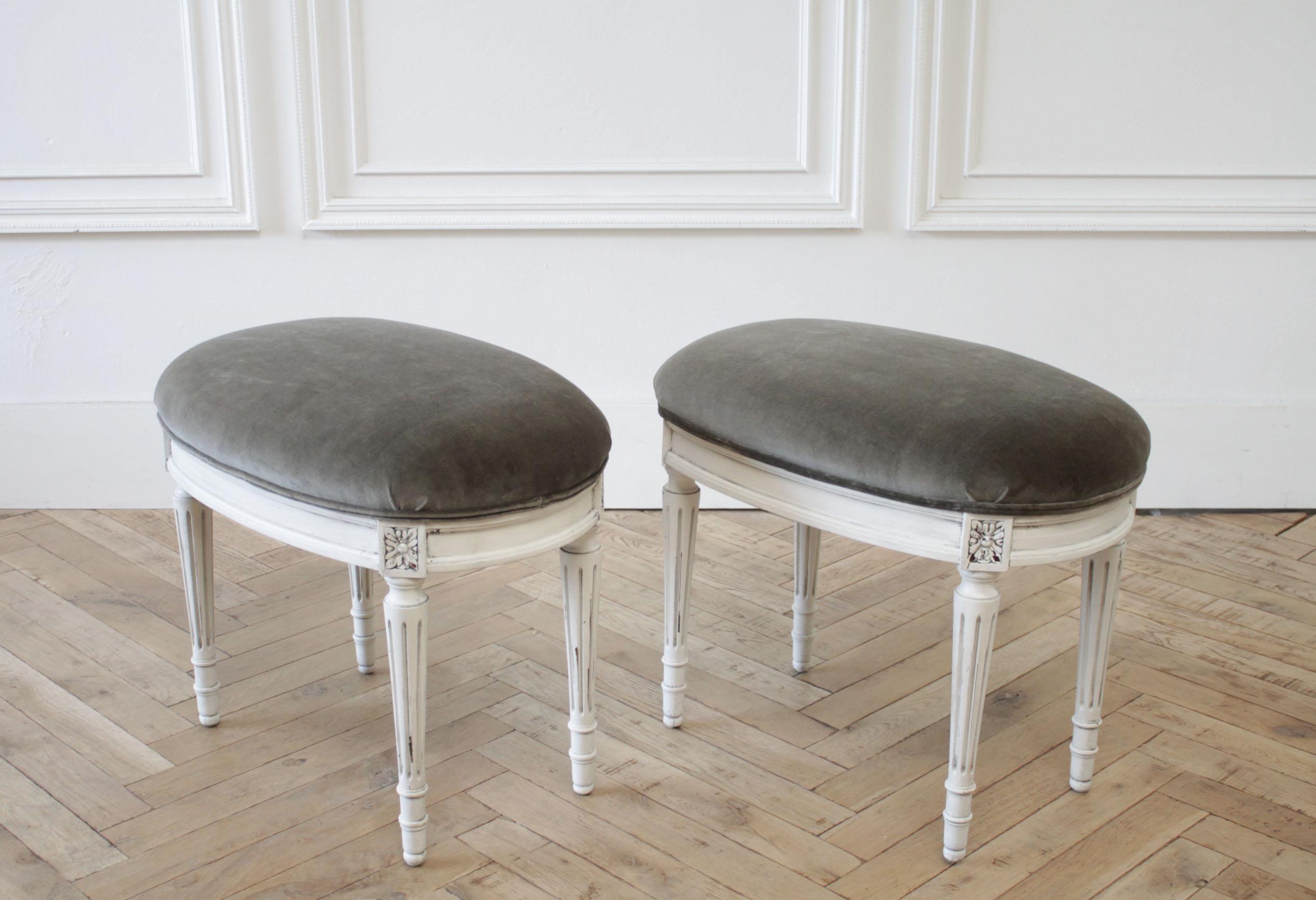 Pair of 20th century Louis XVI style painted and velvet upholstered ottomans
Painted in a soft oyster white, with subtle distressed edges, and antique glazed patina.
These are upholstered in a deep olive-gray vintage style velvet. Upholstery is