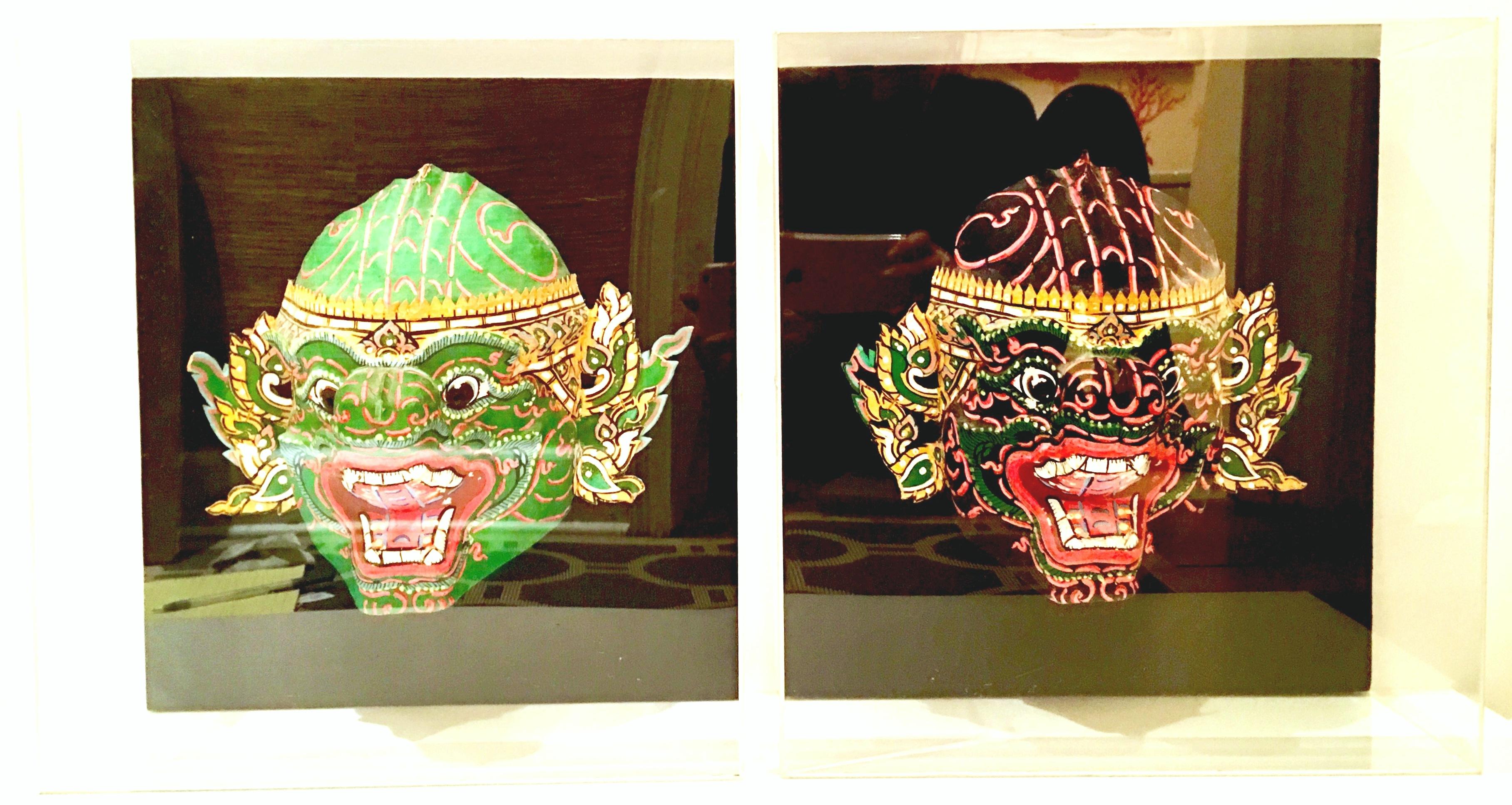 Pair of Javanese papier-mâché hand painted tribal celebration masks. Each mask is mounted on black linen in large Lucite shadow box frames. Each mask measures approximately, 11