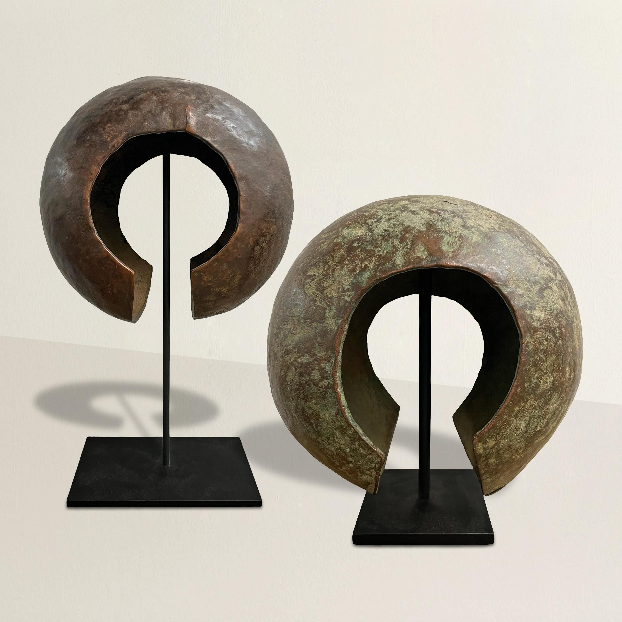 Immerse yourself in the rich cultural of the Mbole people of the Democratic Republic of the Congo with this exquisite pair of 20th-century Mbole copper currency cuffs. Mounted on custom steel stands, these cuffs bear witness to a tradition steeped